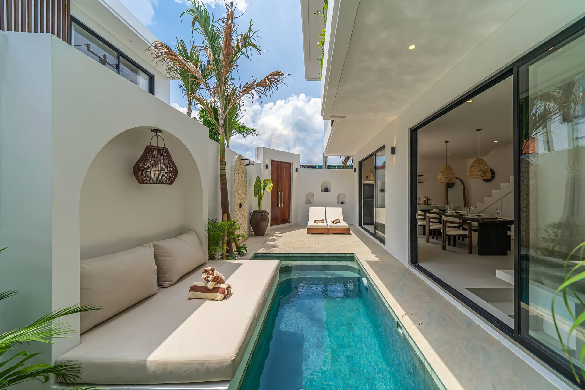 Pool deck and alcove daybed at Nova Oasis 1, with the dining table visible through the glass