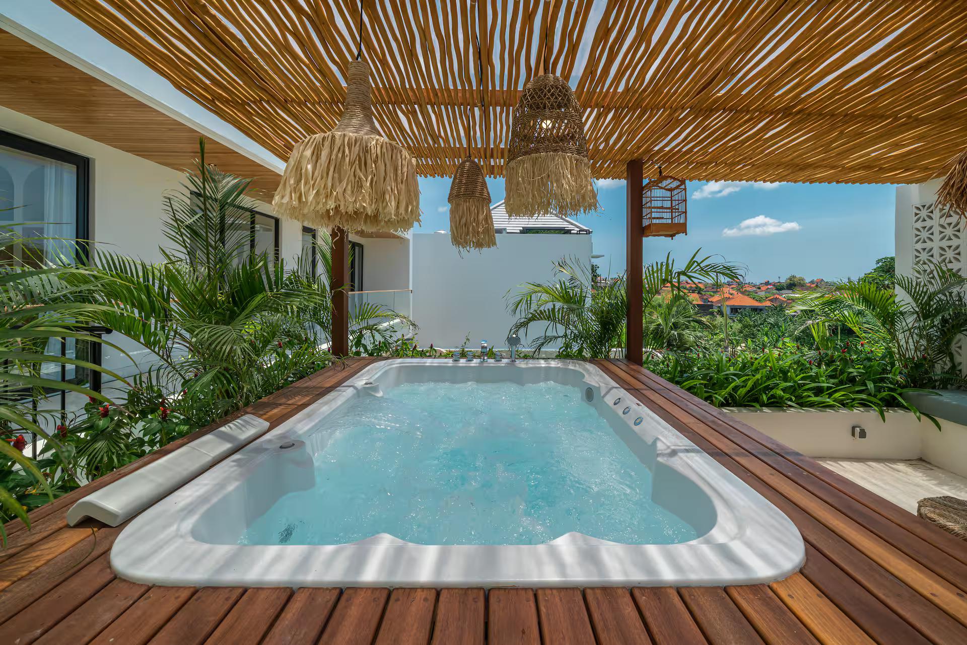 Rooftop jacuzzi on a timber deck under a split-bamboo canopy hung with rattan pendants