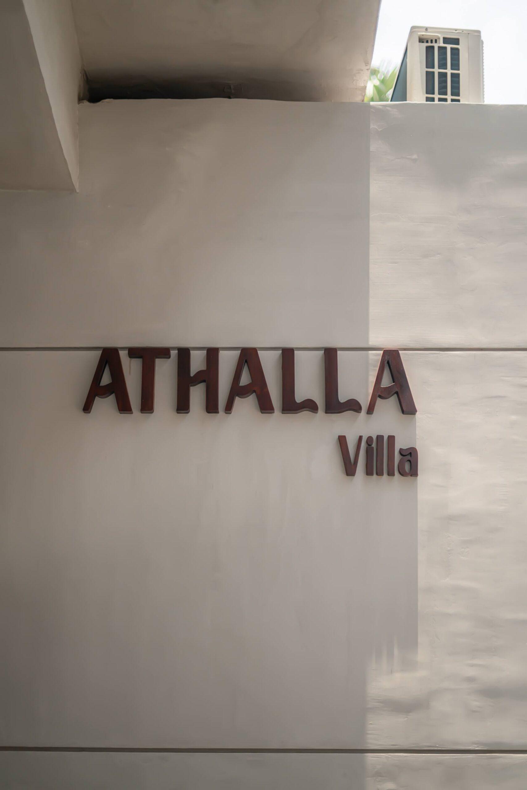Timber letters spelling ATHALLA Villa on the rendered entrance wall of the villa