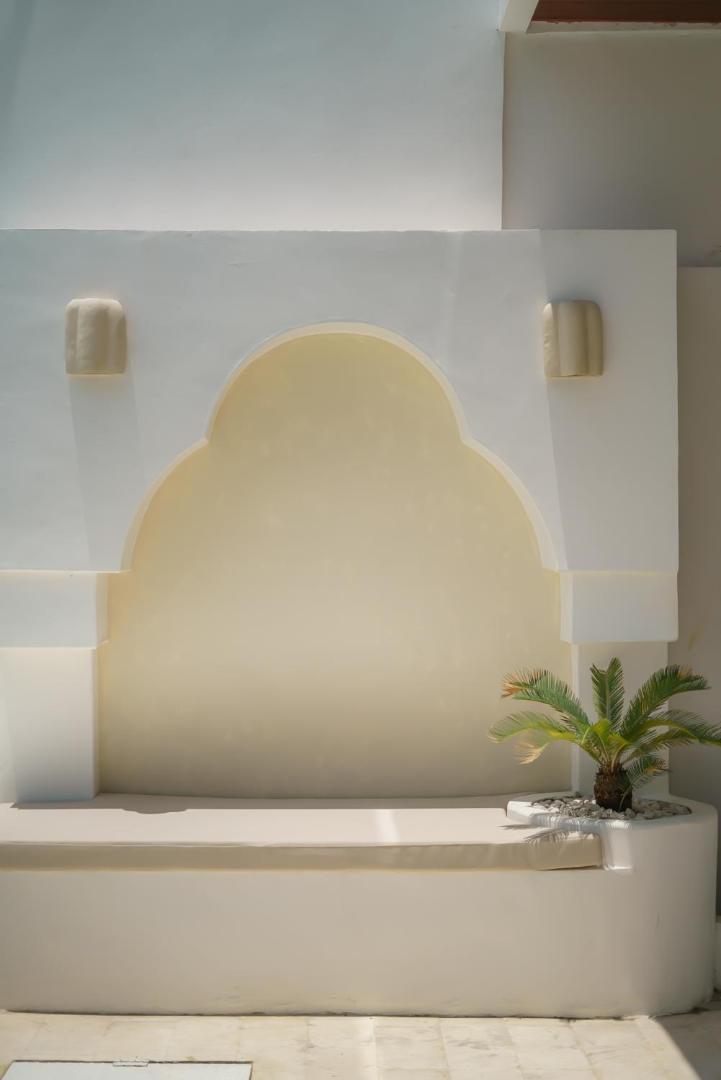 Arched alcove with a built-in bench and a cycad in pebbles at the head of the pool