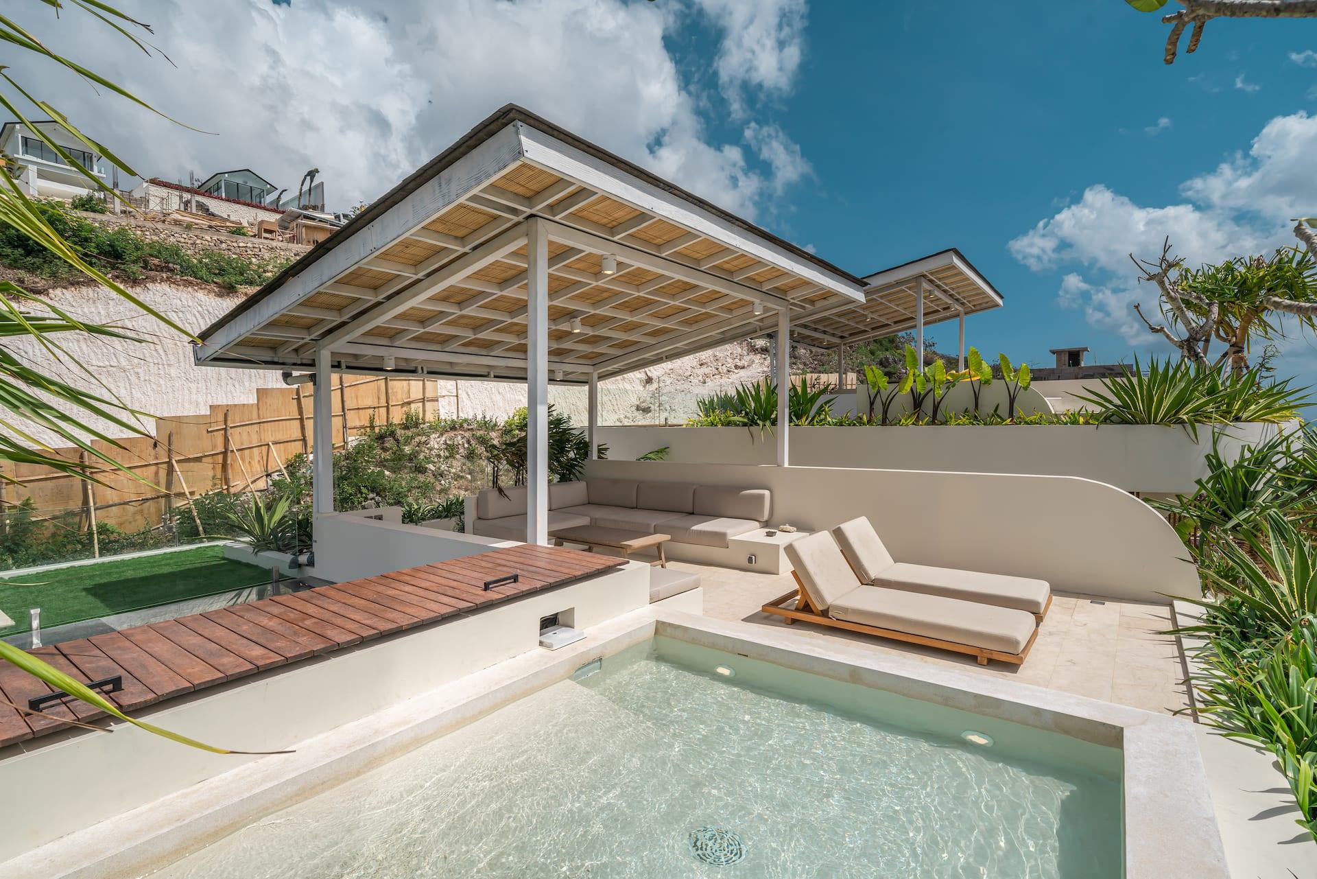 Rooftop plunge pool and timber deck with sun loungers under a shaded white pavilion