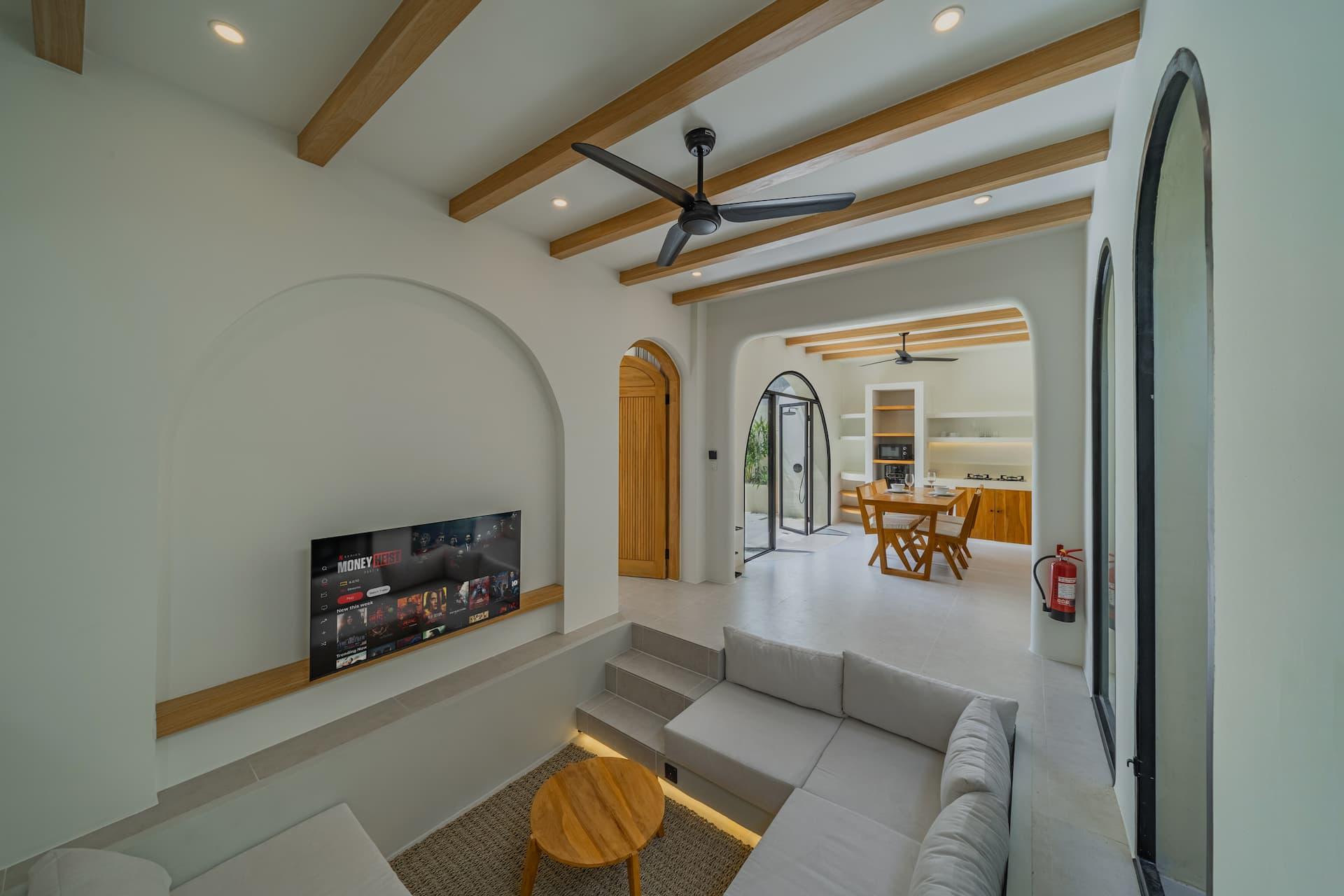 Sunken lounge seen from above, with a TV set into an arched niche and timber beams overhead