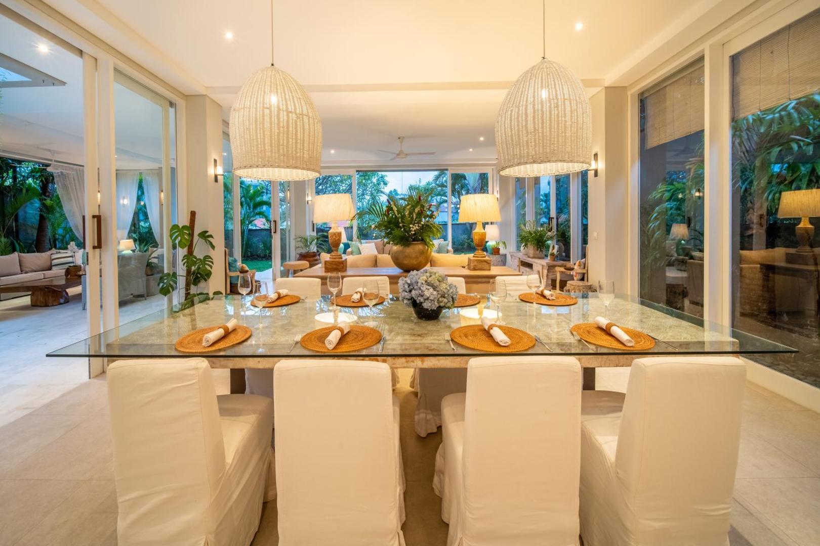 Glass-topped dining table laid for eight beneath woven rattan pendants at Villa Sunsara 4