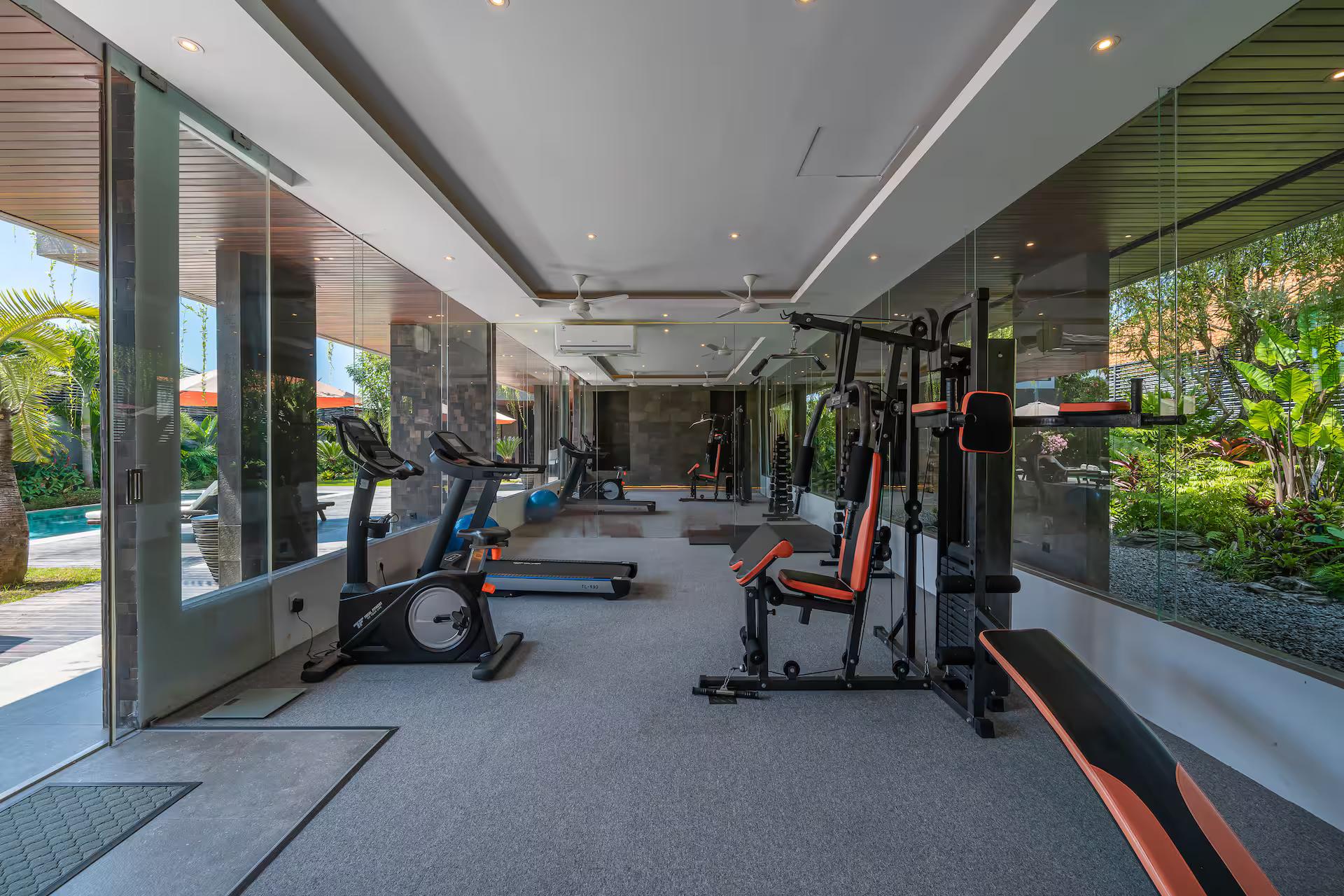 Private gym with a multi-station rig and treadmill, glazed to the garden on two sides