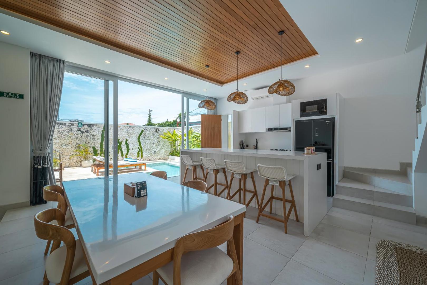 Dining table and kitchen bar with the pool visible through the sliding doors