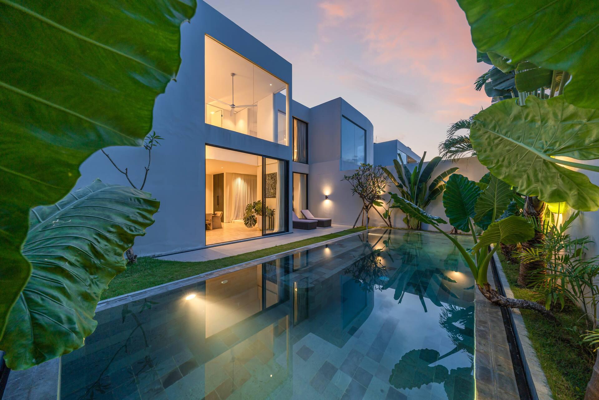 Villa Kiyoji at twilight, the double-height window wall glowing above the still pool