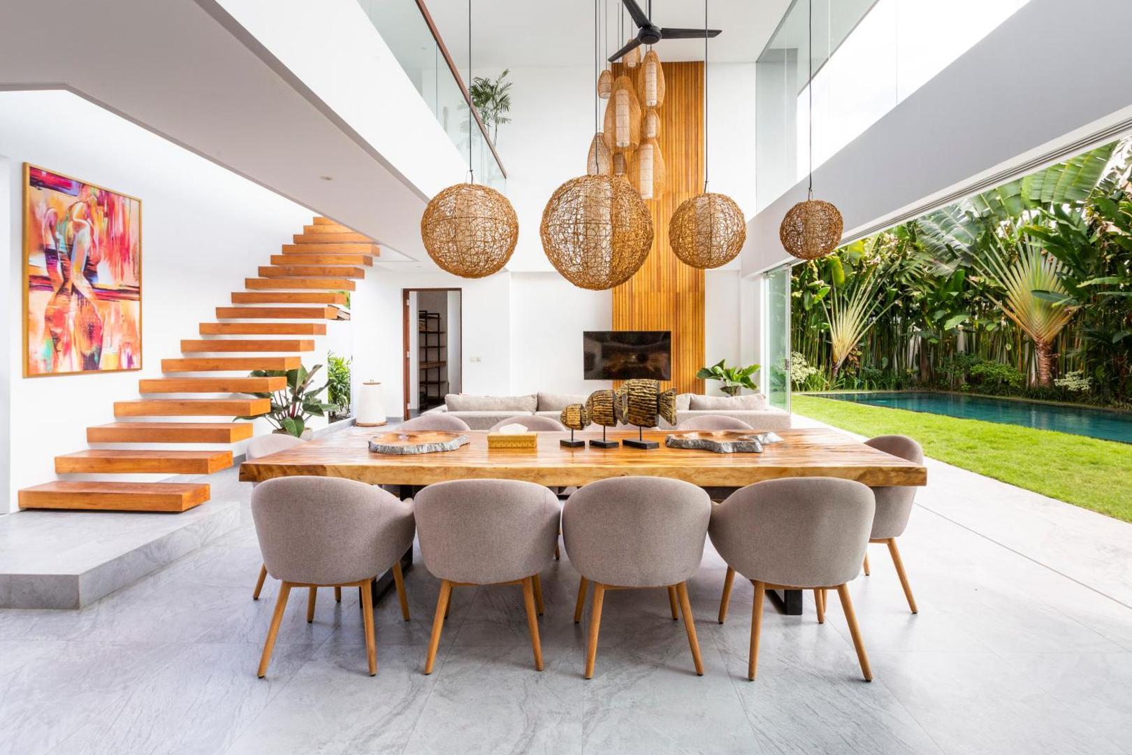 Live-edge dining table for ten under woven rattan globes beside the timber stair