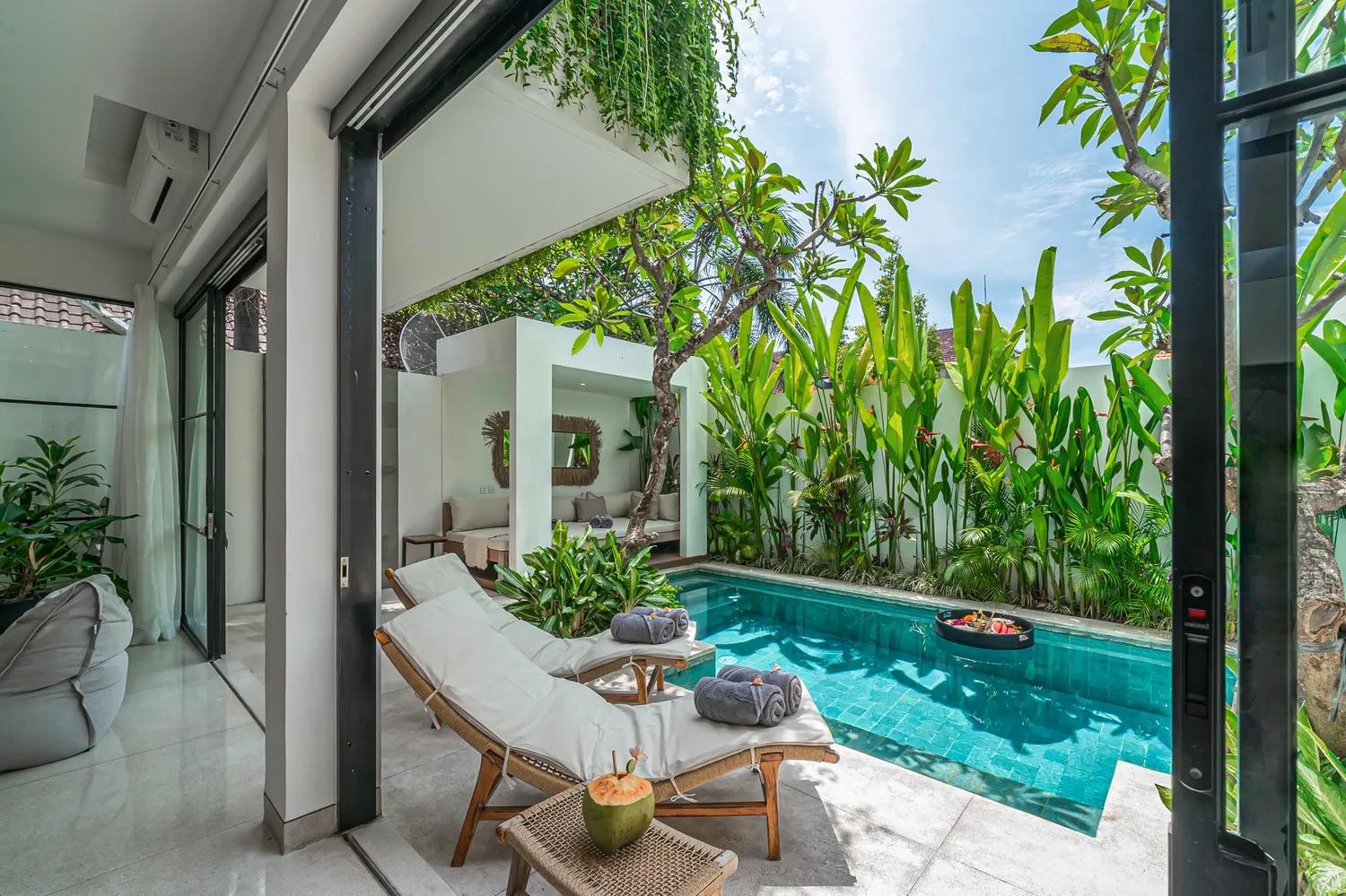 Timber sun loungers and rolled towels beside the pool at Villa Puri Senang