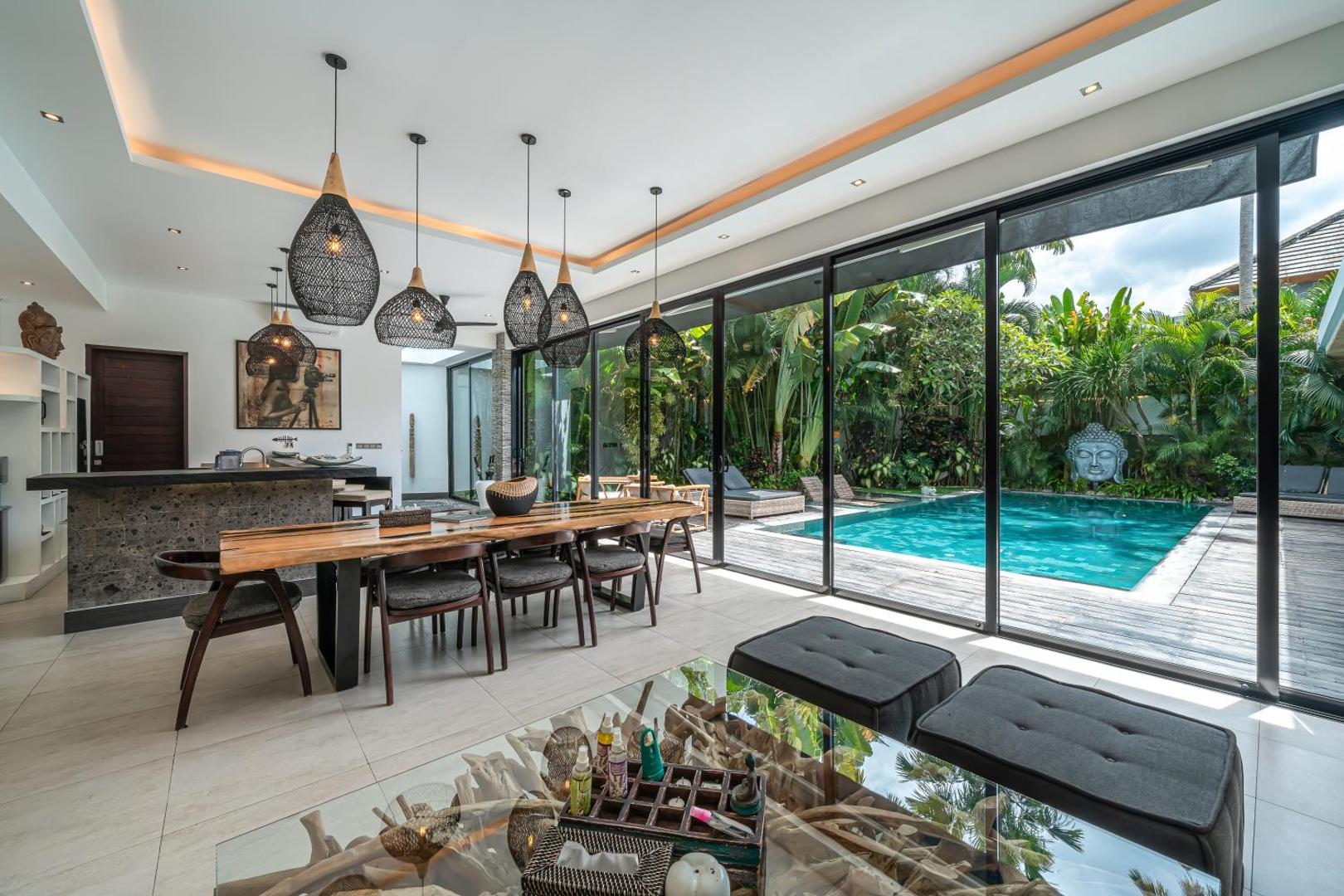 Live-edge slab dining table at Villa Marlon under a row of black wire-cage pendants