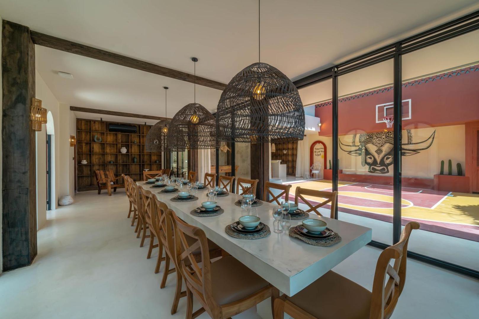 The long dining table for fourteen, laid and looking out to the basketball court