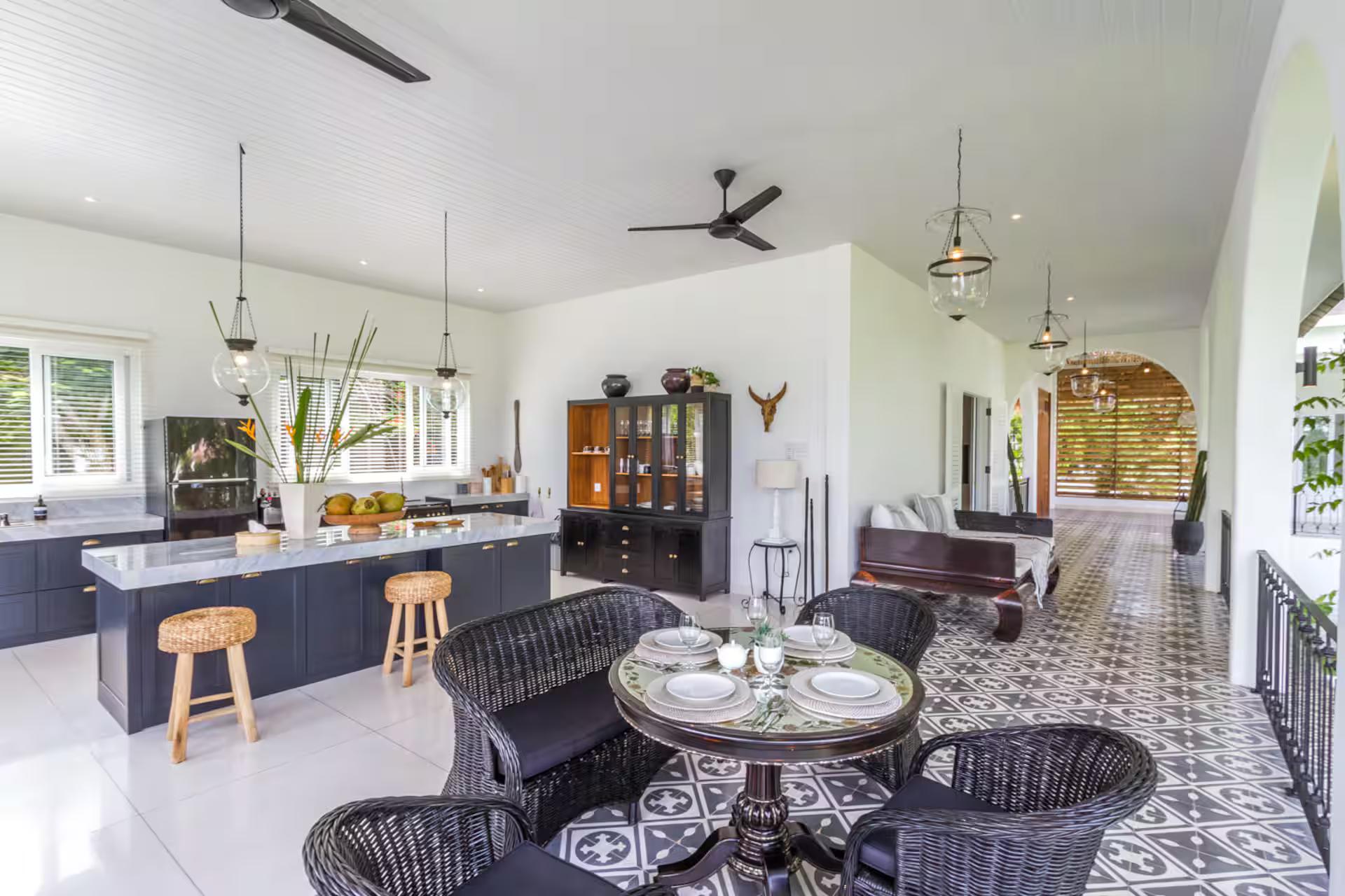 Kitchen island with timber bar stools and the round dining table beyond it