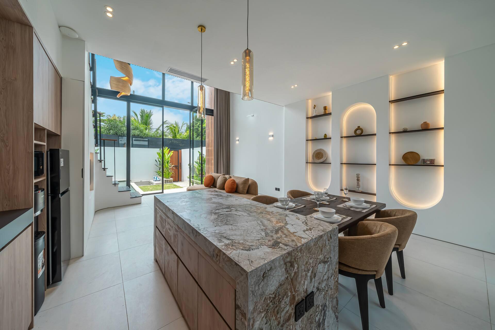 Marble-topped kitchen island and dining table at Fire Villa Berawa, glazed wall onto the pool