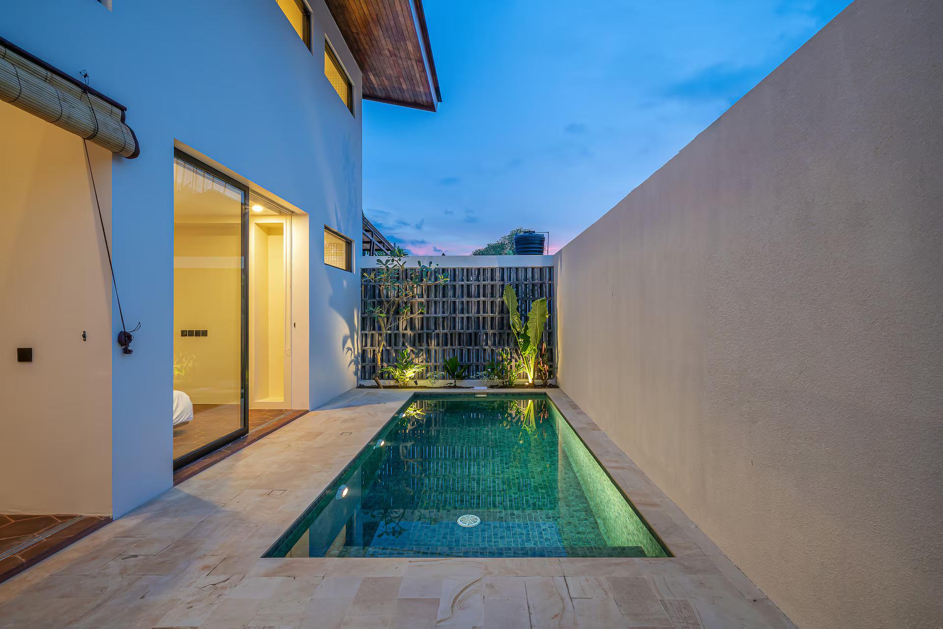 Villa Fonda after sunset, the pool lit green against a perforated breeze-block screen