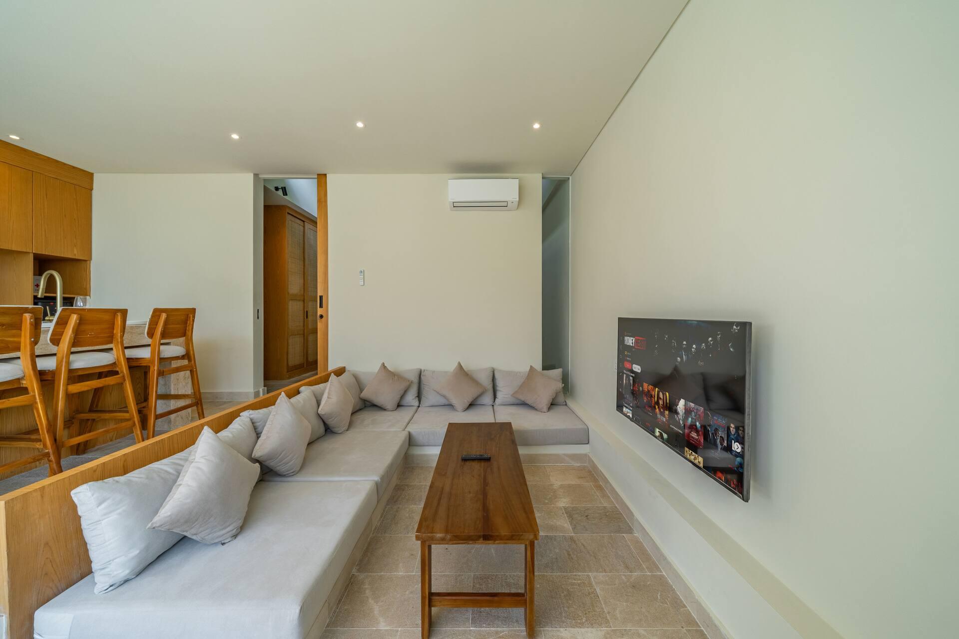 Linen banquette and teak coffee table facing the television at Villa Aura