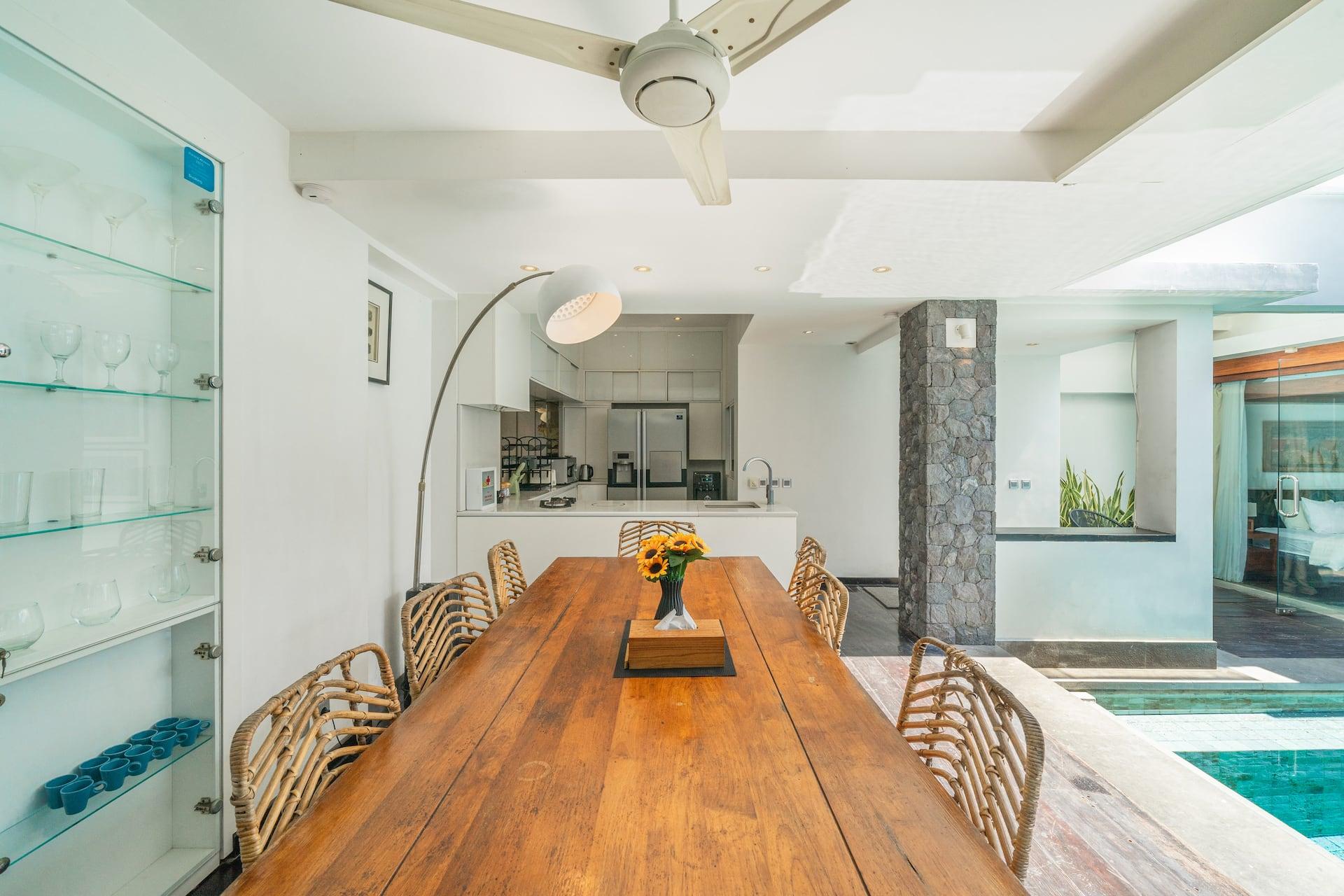 Long timber dining table for eight beside the glassware cabinetry at Villa Tykhe