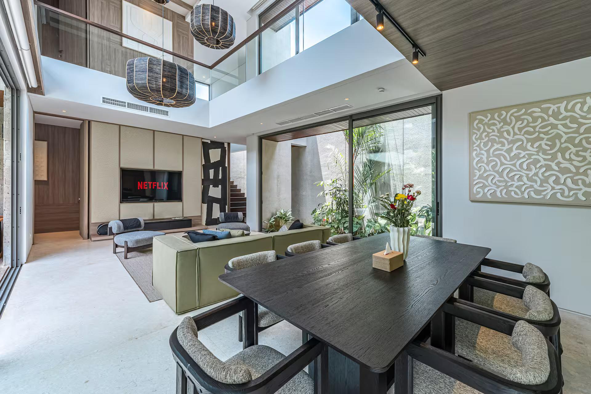 Dining table for eight in dark timber, the lounge and pool visible beyond