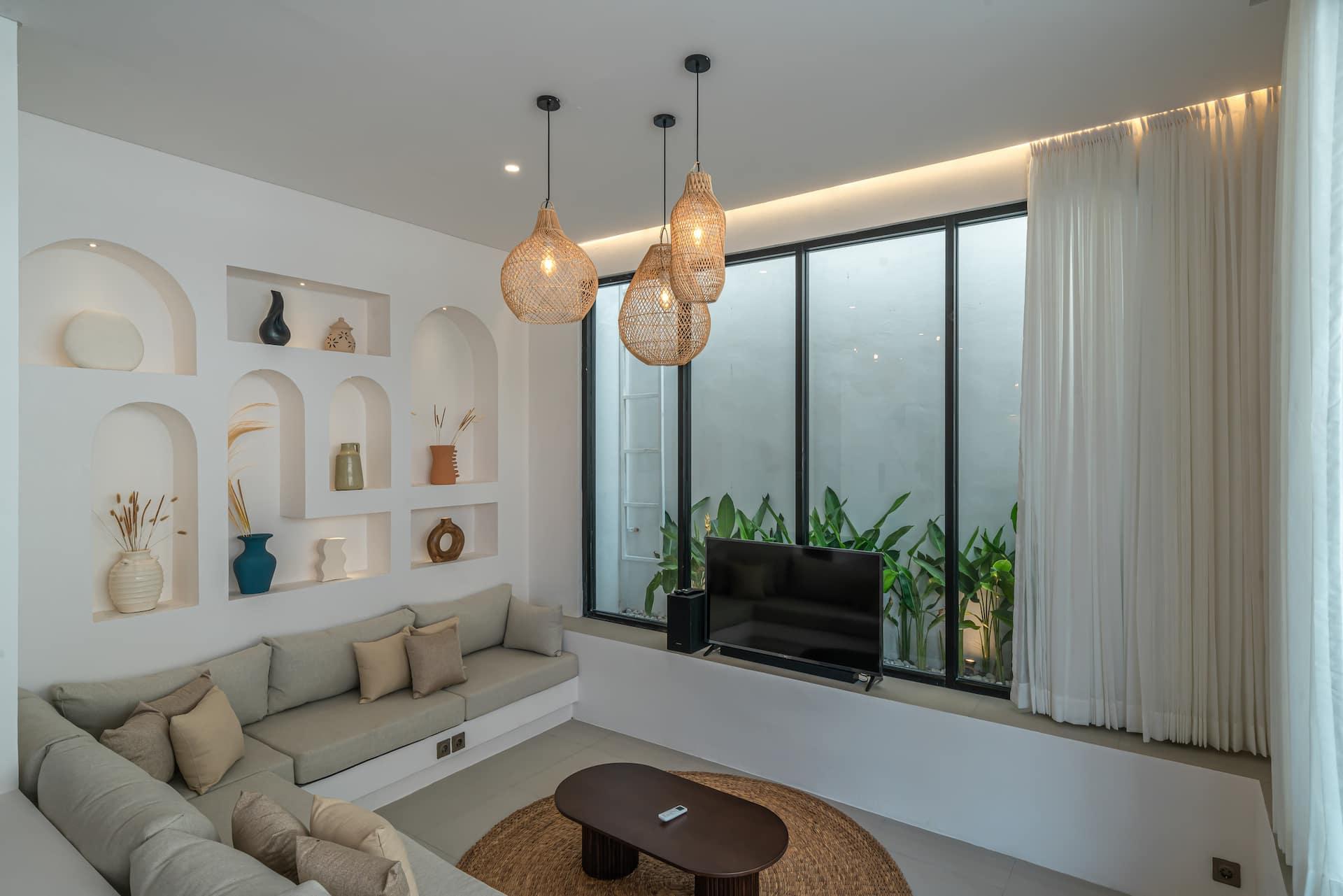 Living room wall of arched niches beside the wall-mounted television and cream banquette