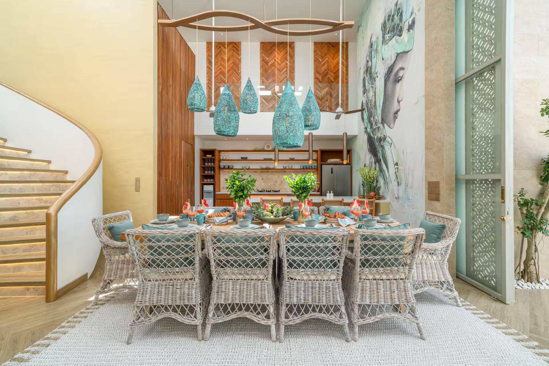 Dining table for ten under blue-green ceramic pendants beside the spiral staircase