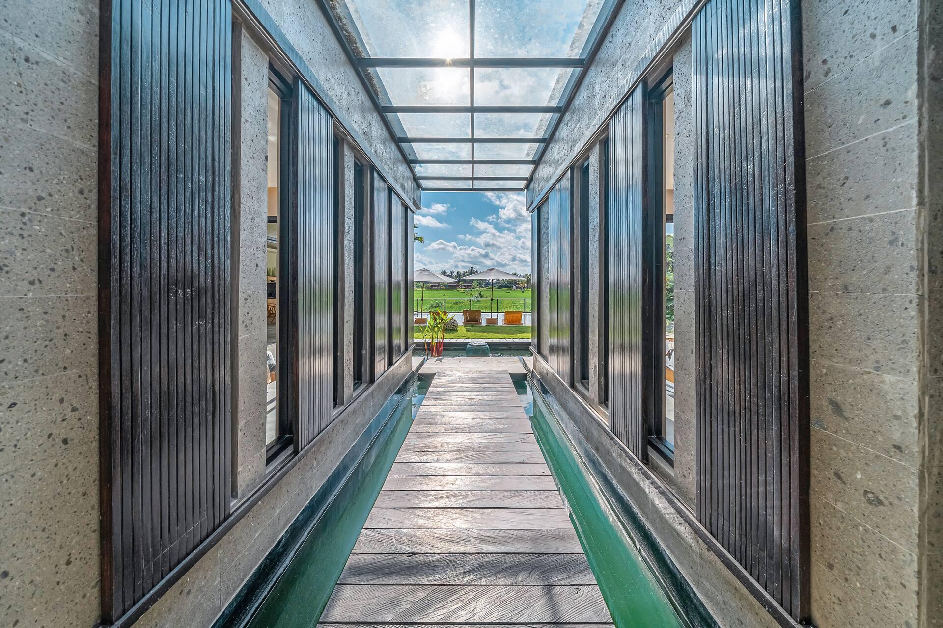 Timber walkway running between the wings of Villa Bliss above a black-lined lily pond