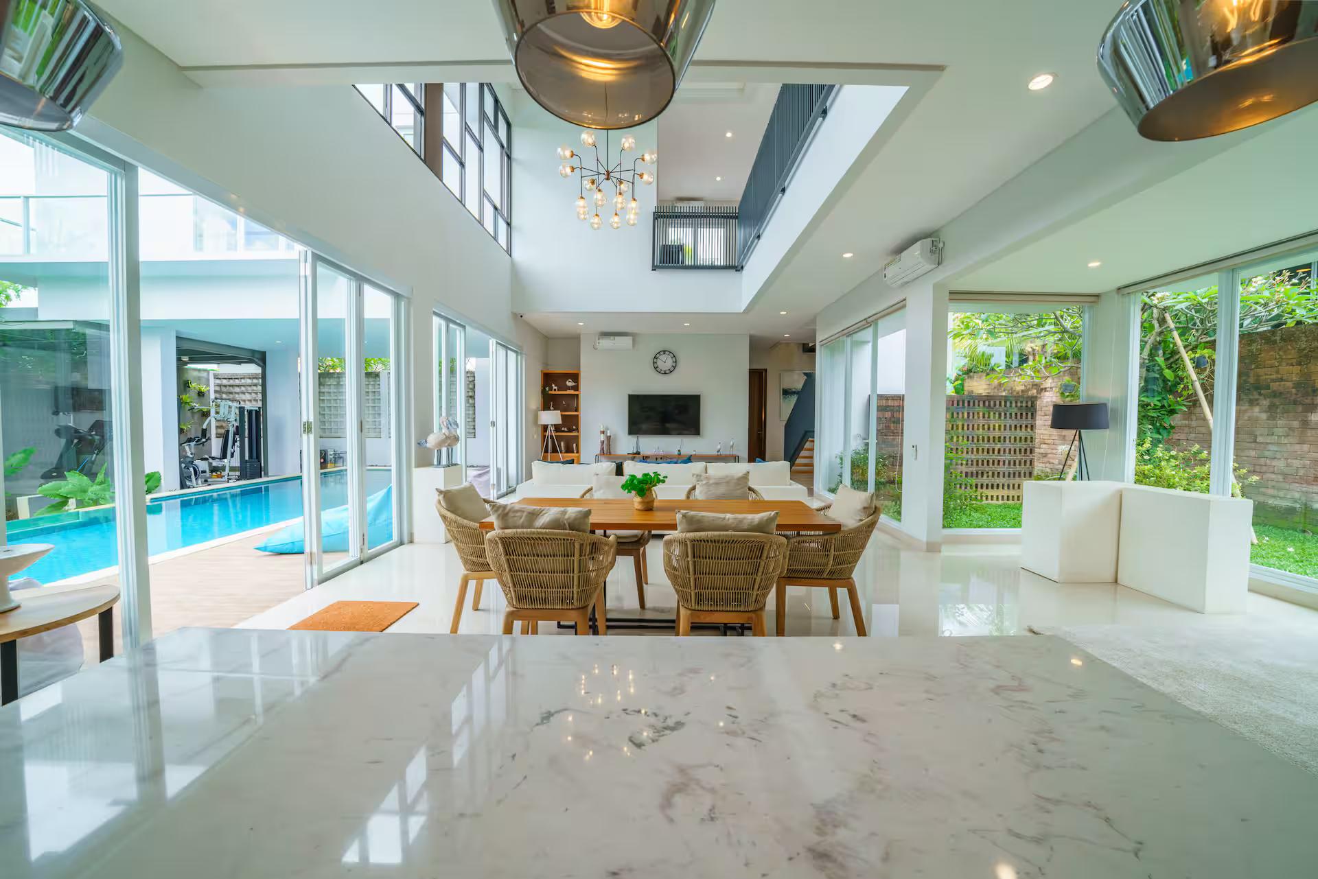 Dining table and kitchen island under the clerestory windows, pool through the doors