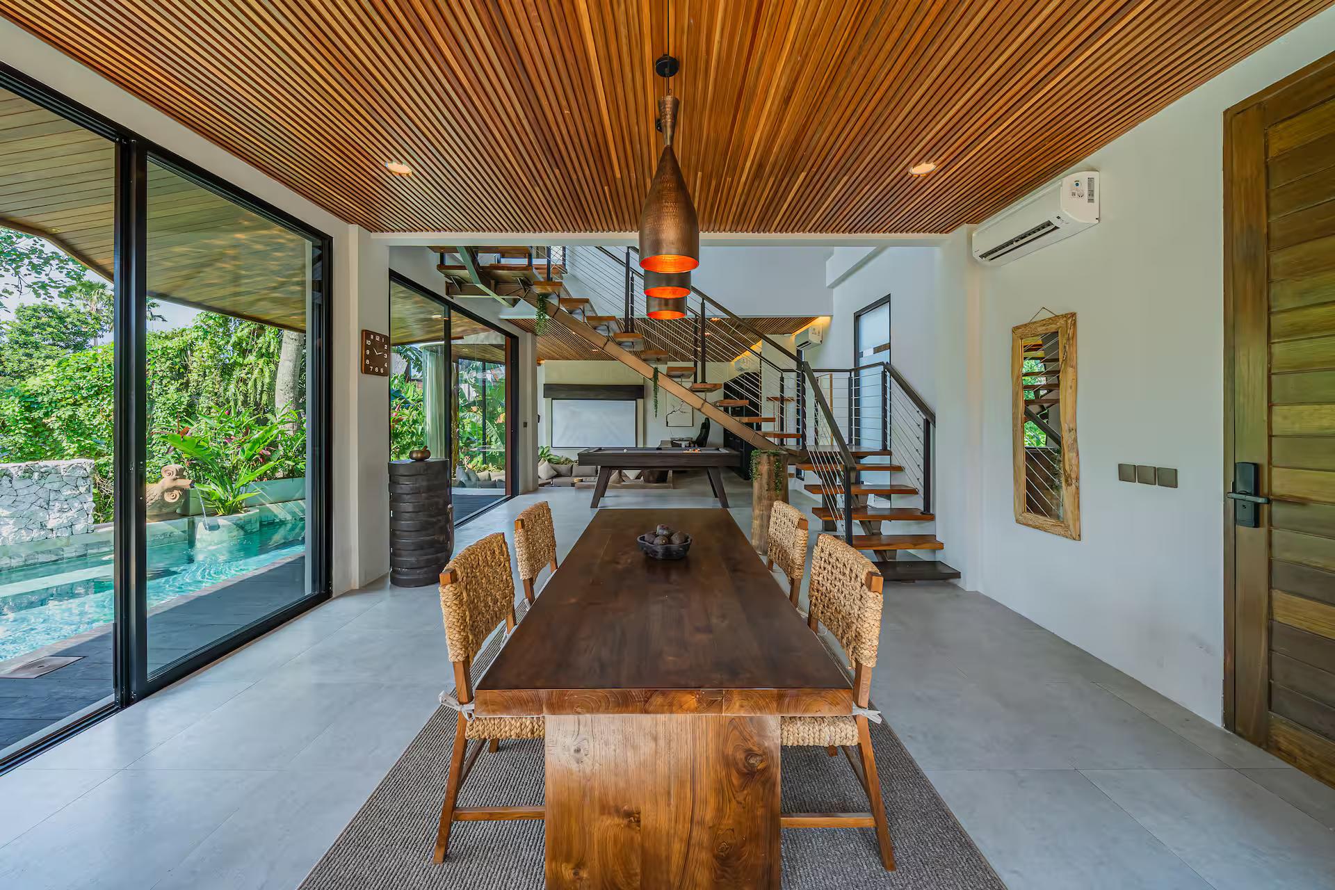 Live-edge timber dining table and woven chairs beside the black steel staircase