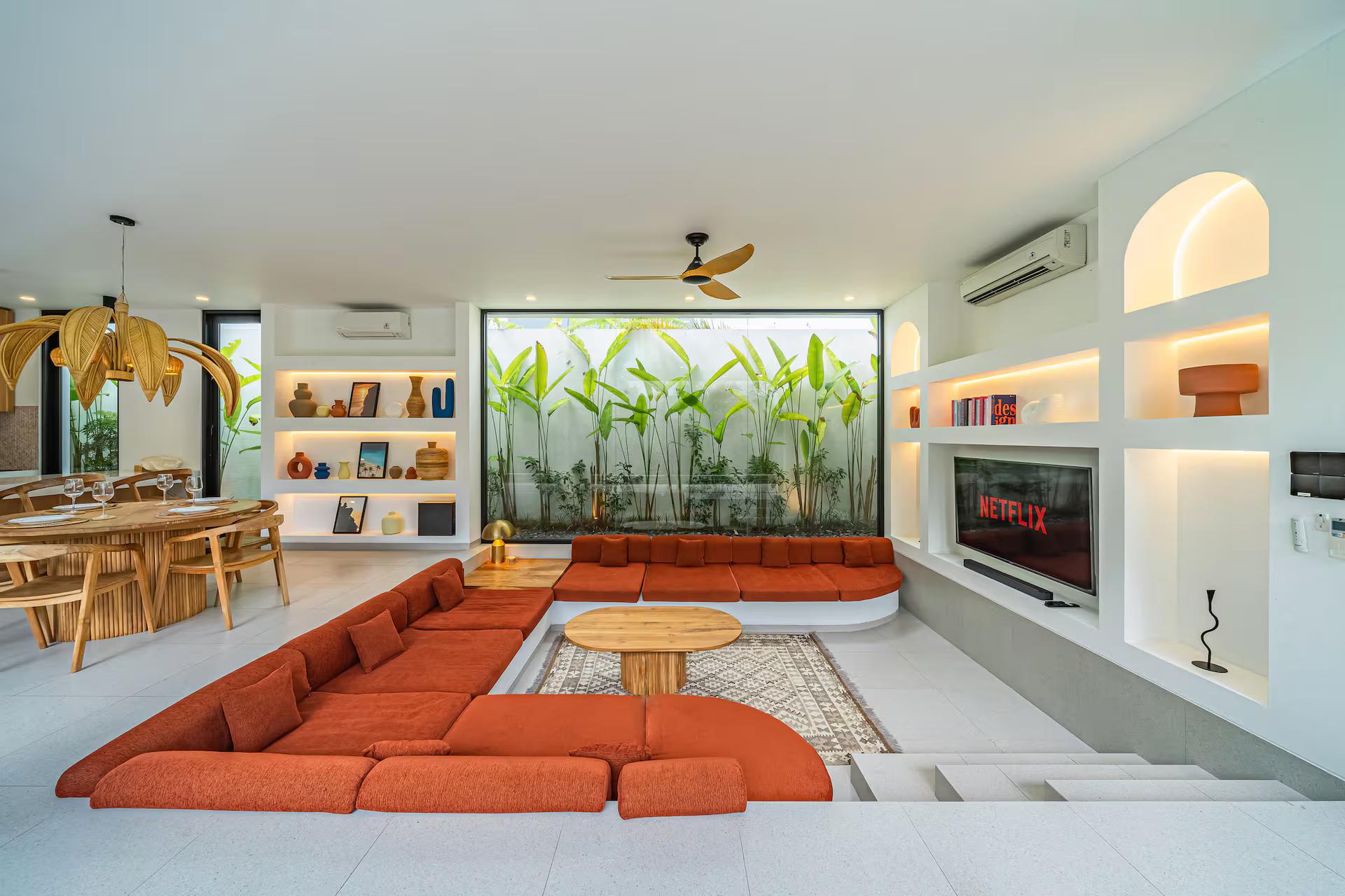 Terracotta modular seating sunk into the floor of a second living room, facing a recessed media niche