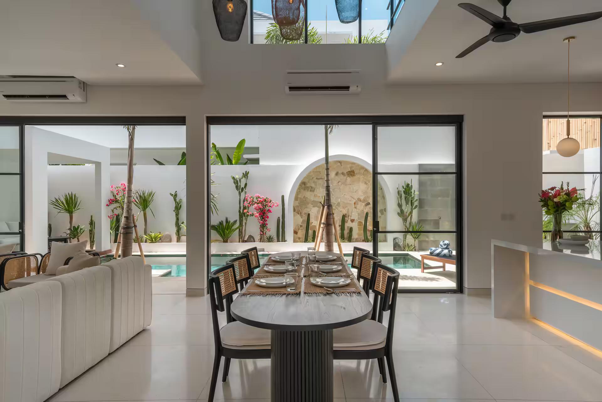 The oval dining table at Casa Embra, glass sliding open onto the courtyard pool