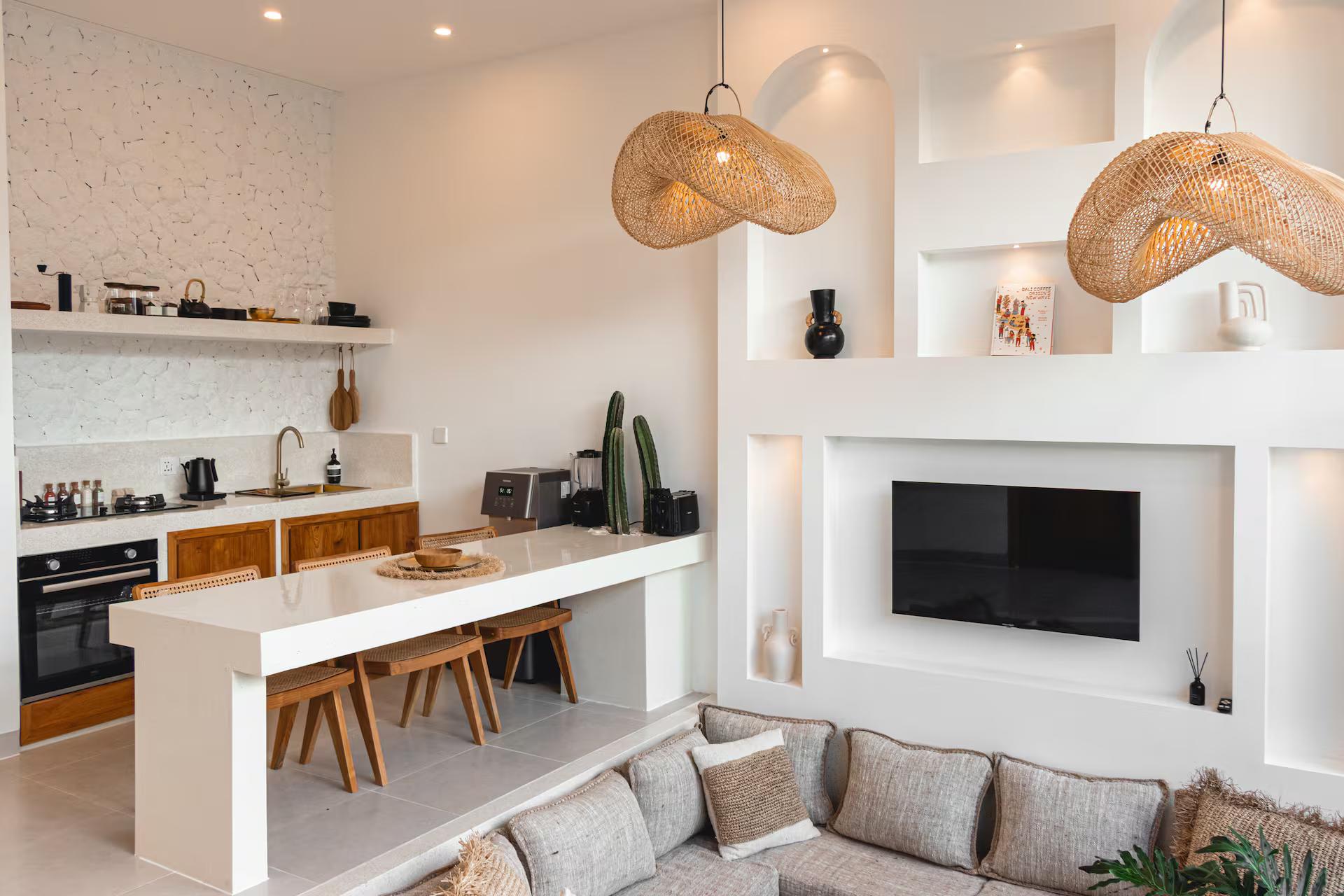 Kitchen counter and breakfast bar under woven pendants, with the sunken living seating beyond