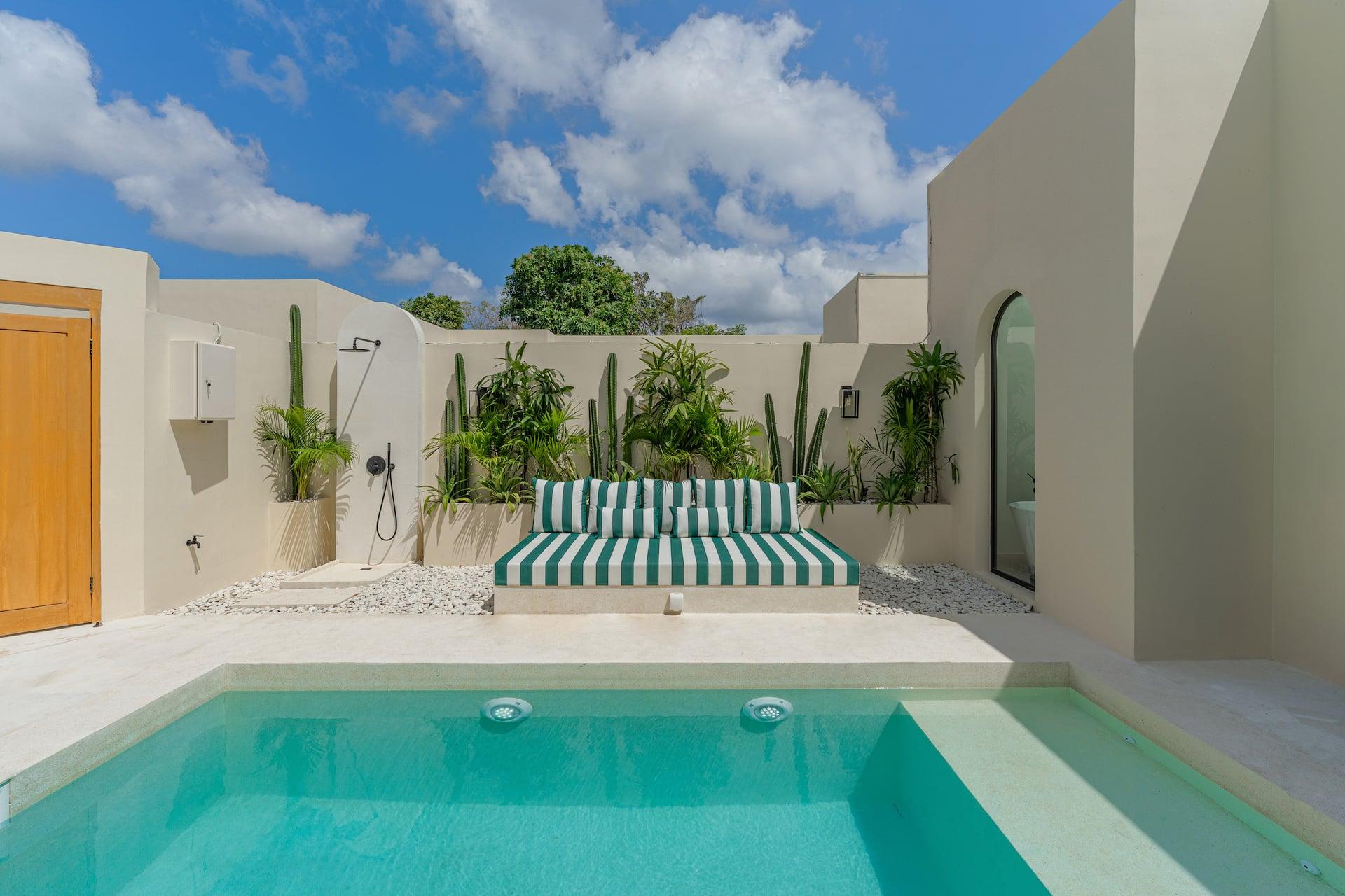Built-in striped daybed and outdoor rain shower beside the pool, framed by cacti and tall palms