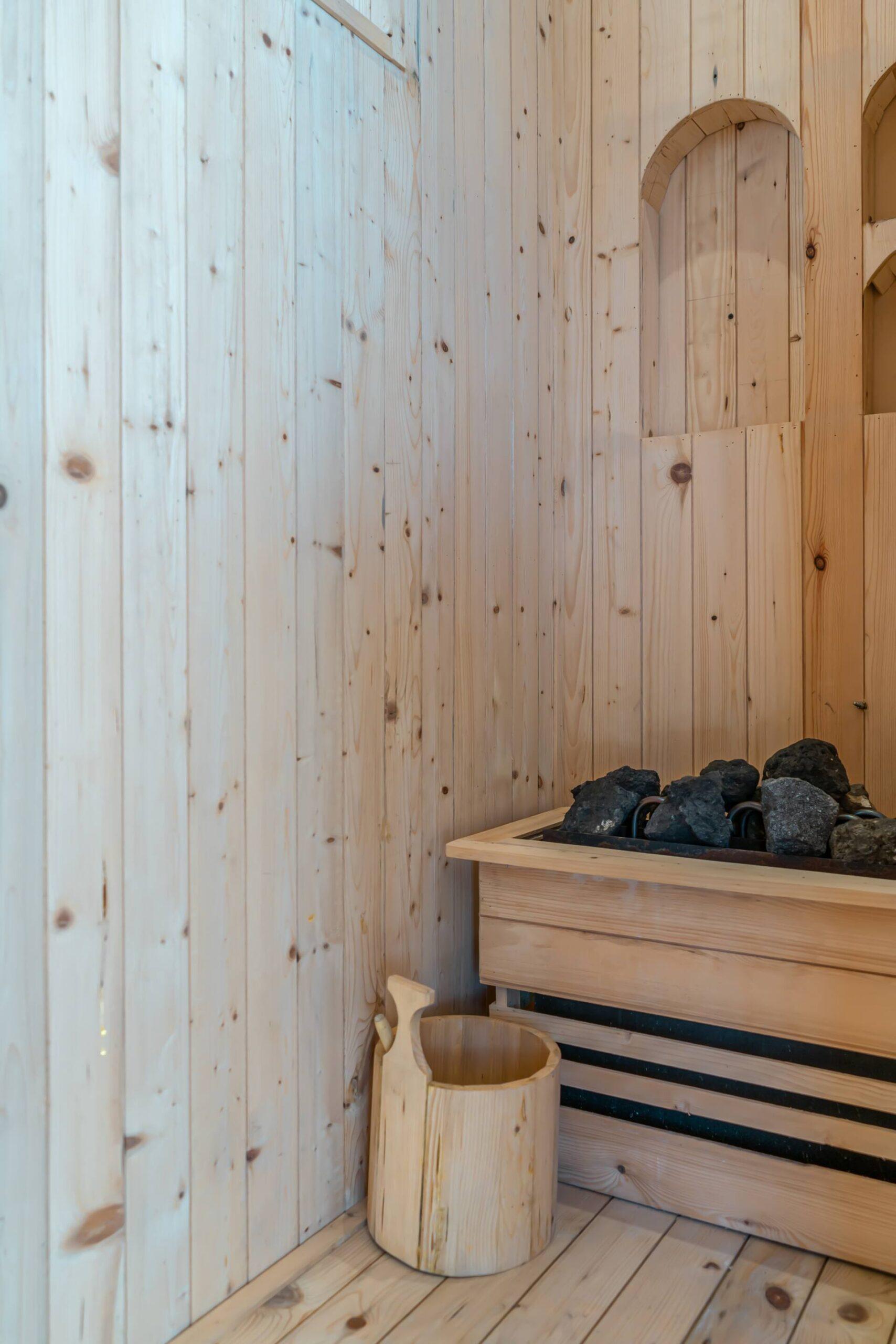 Pine-lined private sauna with a coal stove and timber bucket on the roof of Villa Dharma