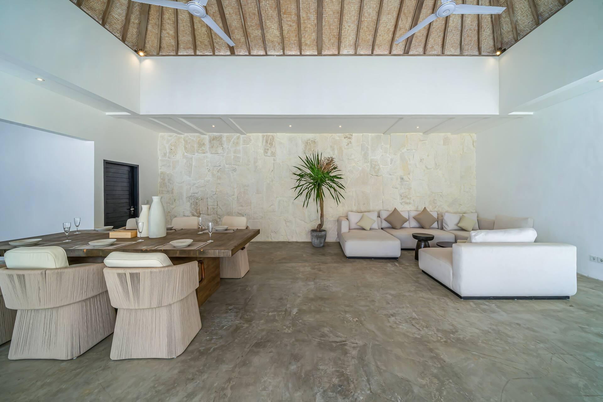 Open-plan living and dining room under a vaulted ceiling of exposed timber beams and thatch