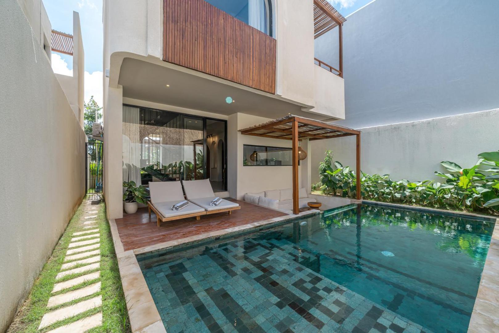 Stepping-stone path along the pool to a timber sun deck with two loungers at the garden end
