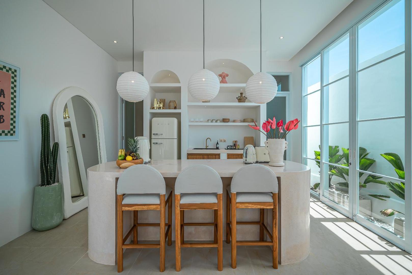 Curved microcement kitchen island with cane-backed stools at Villa Halo
