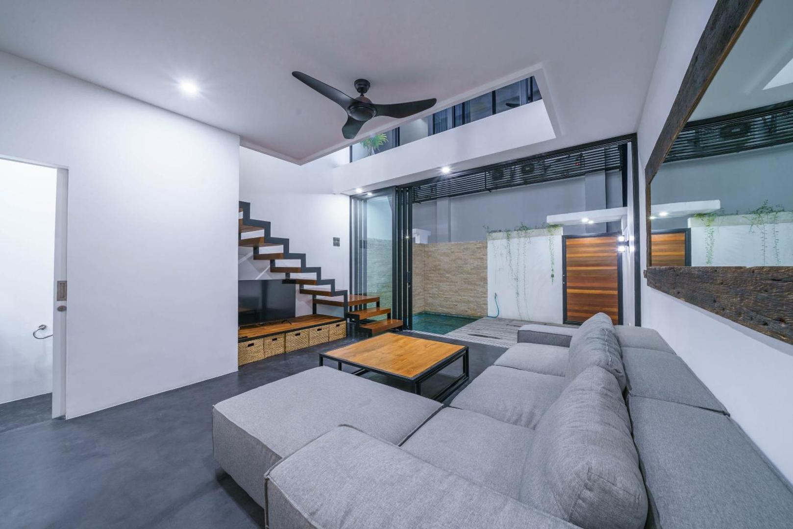Living room open the full width to the deck, the plunge pool bright beyond the glass