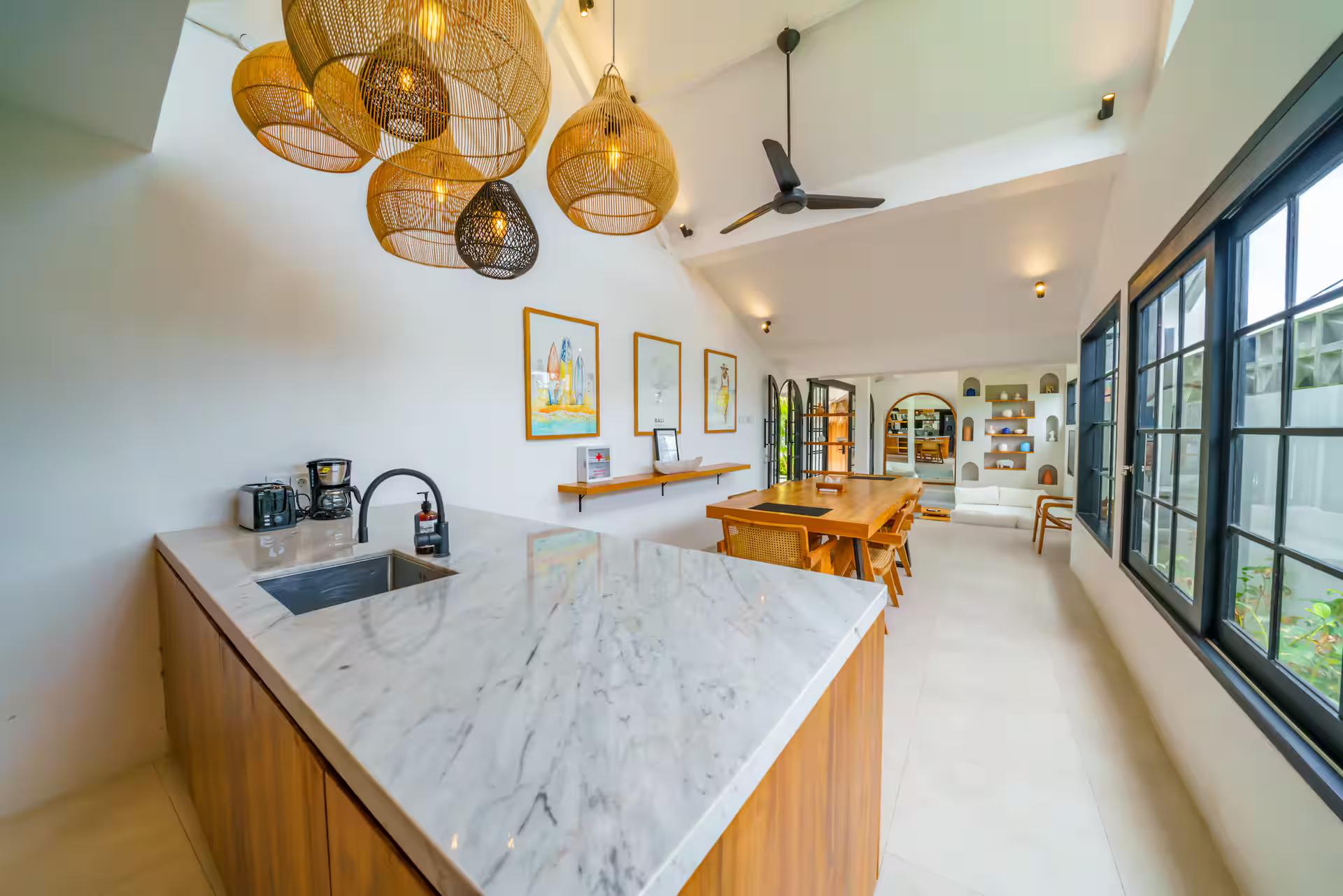 White marble island on timber cabinetry with woven and black glass pendants above