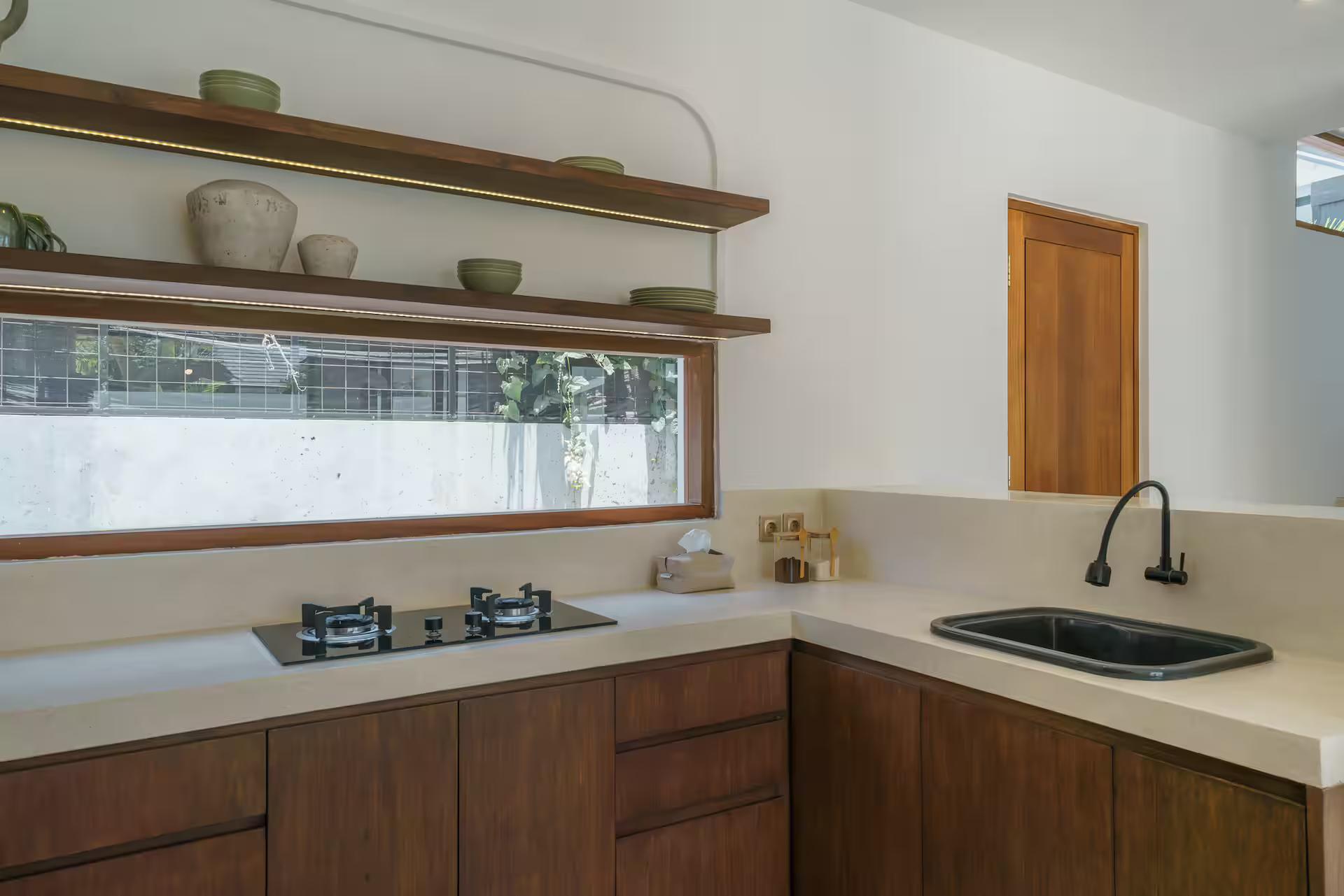 Kitchen at Villa Umaju in dark timber cabinetry with a gas hob and pale stone benchtop