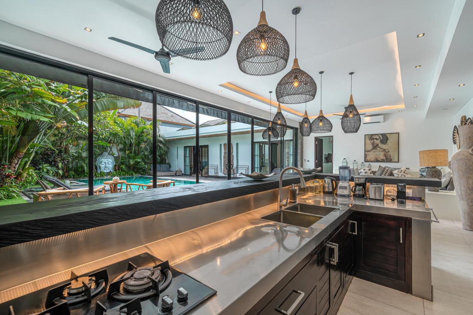 Gas hob set into the dark stone kitchen counter, with a service bar over the pool