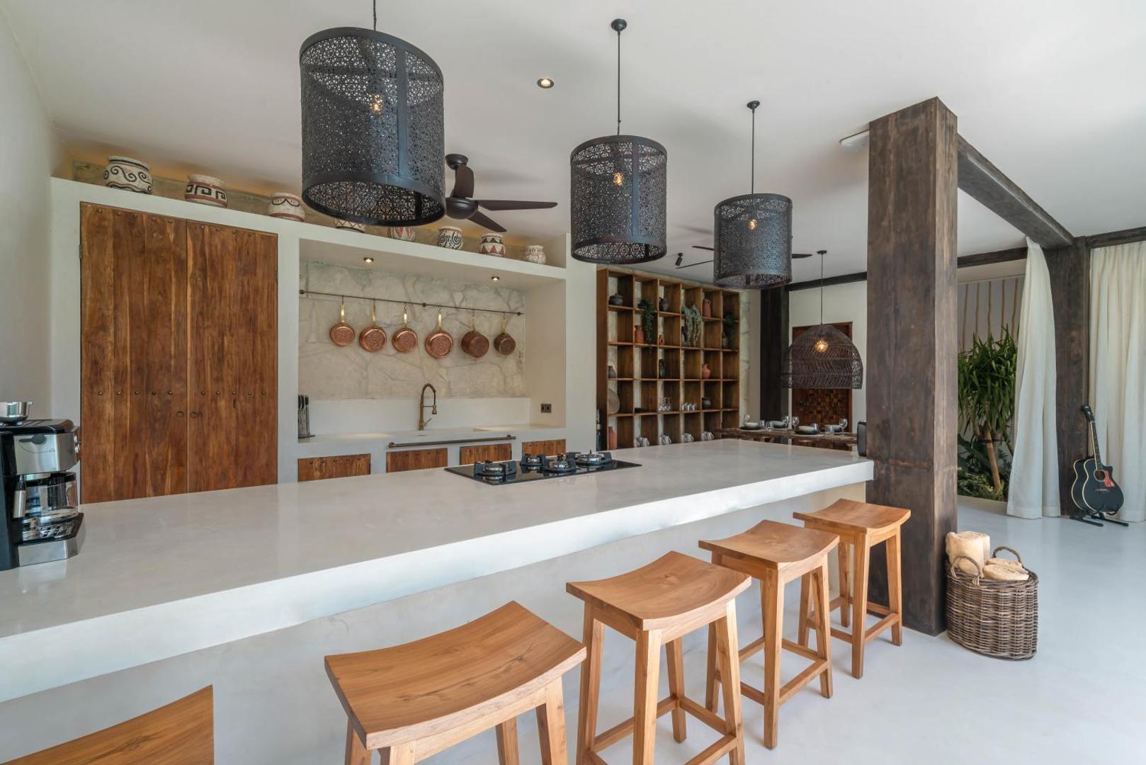 Kitchen island poured in white concrete with timber stools and copper pans on stone