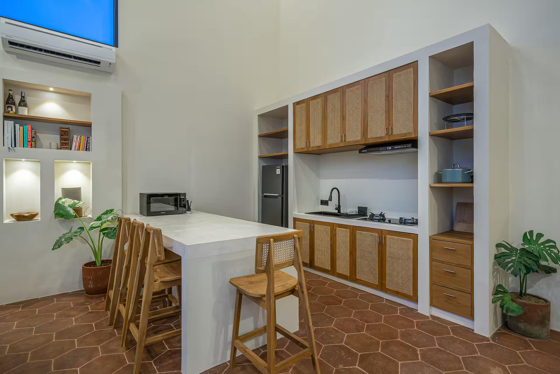 Kitchen island in white stone with cane-fronted cabinets and timber bar stools