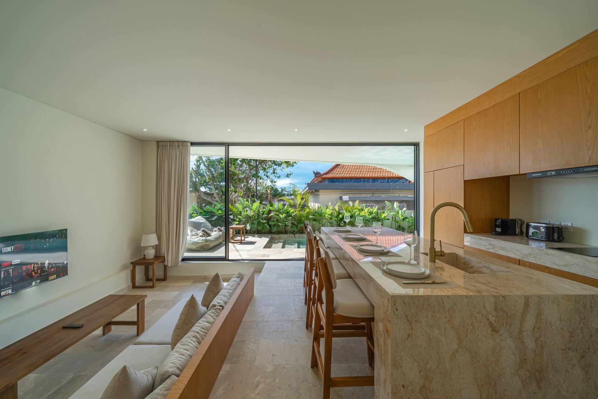 Villa Aura's travertine kitchen island looking out through the glass to the garden