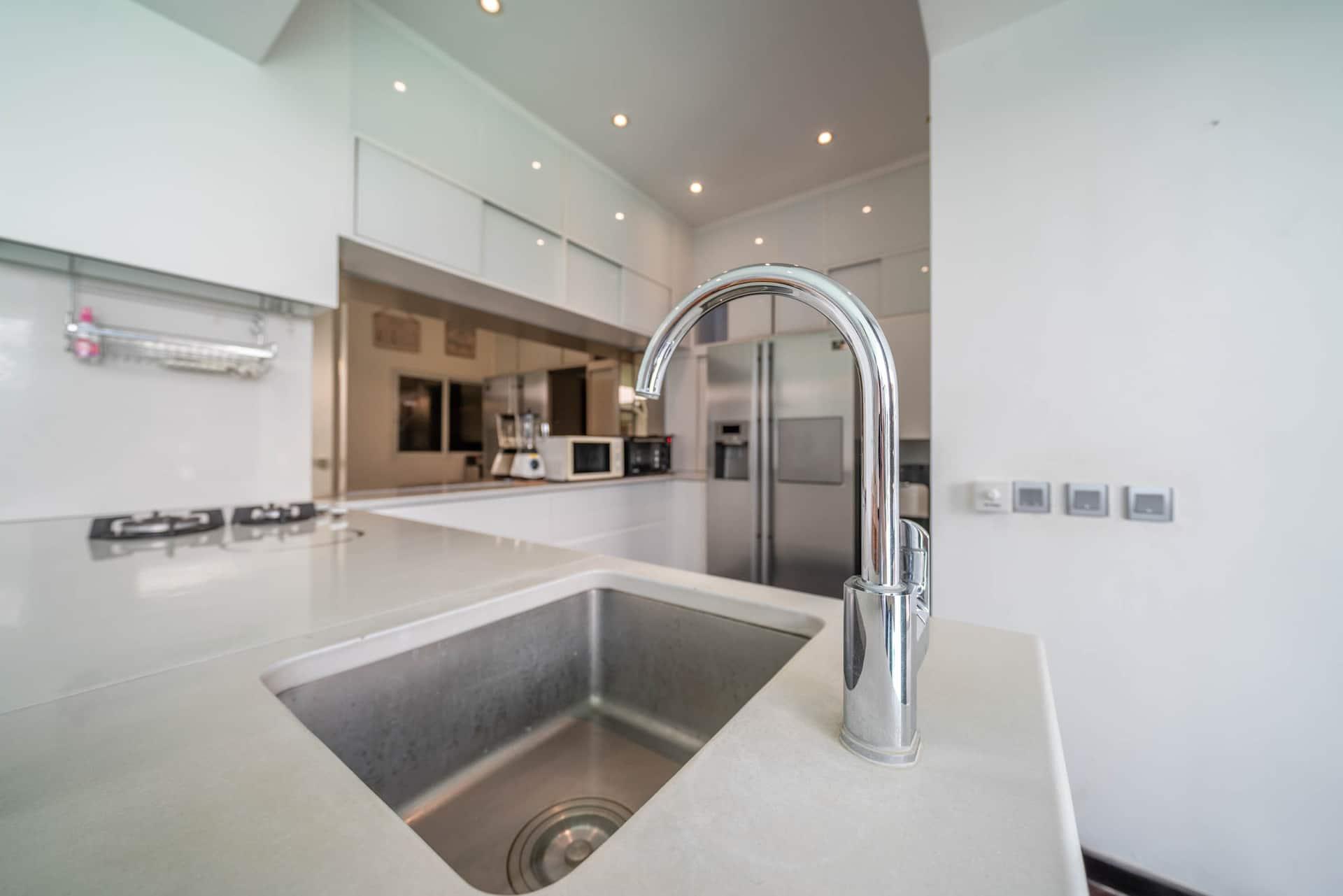 Stone-topped kitchen island with an integrated sink and full-height white joinery