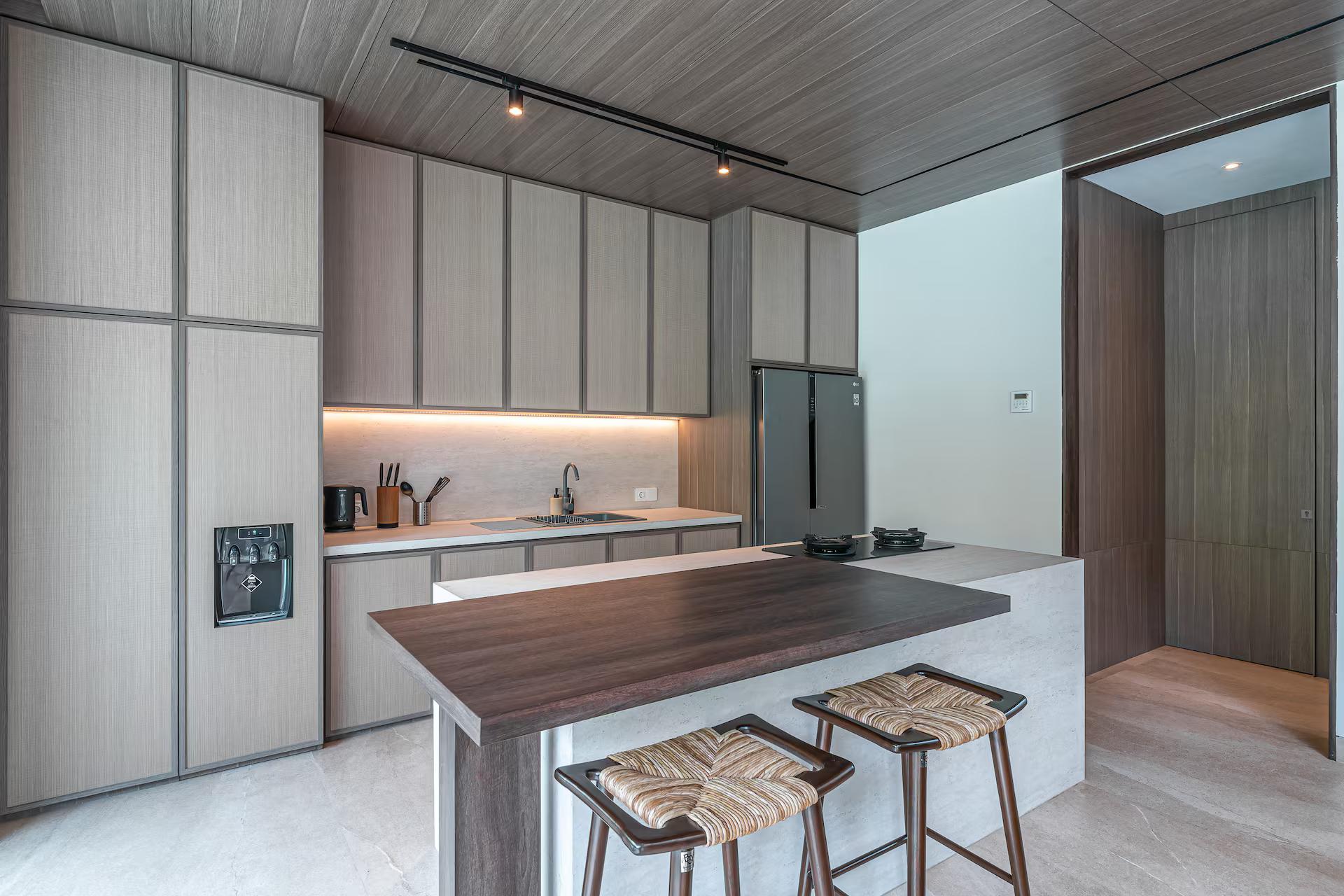 Kitchen island in pale stone with woven stools at Villa Akar & Daun