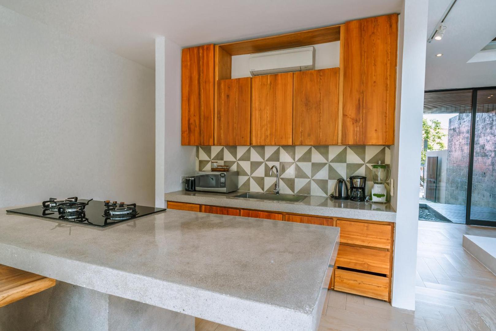 Concrete kitchen island with a gas hob against a geometric triangle-tile splashback