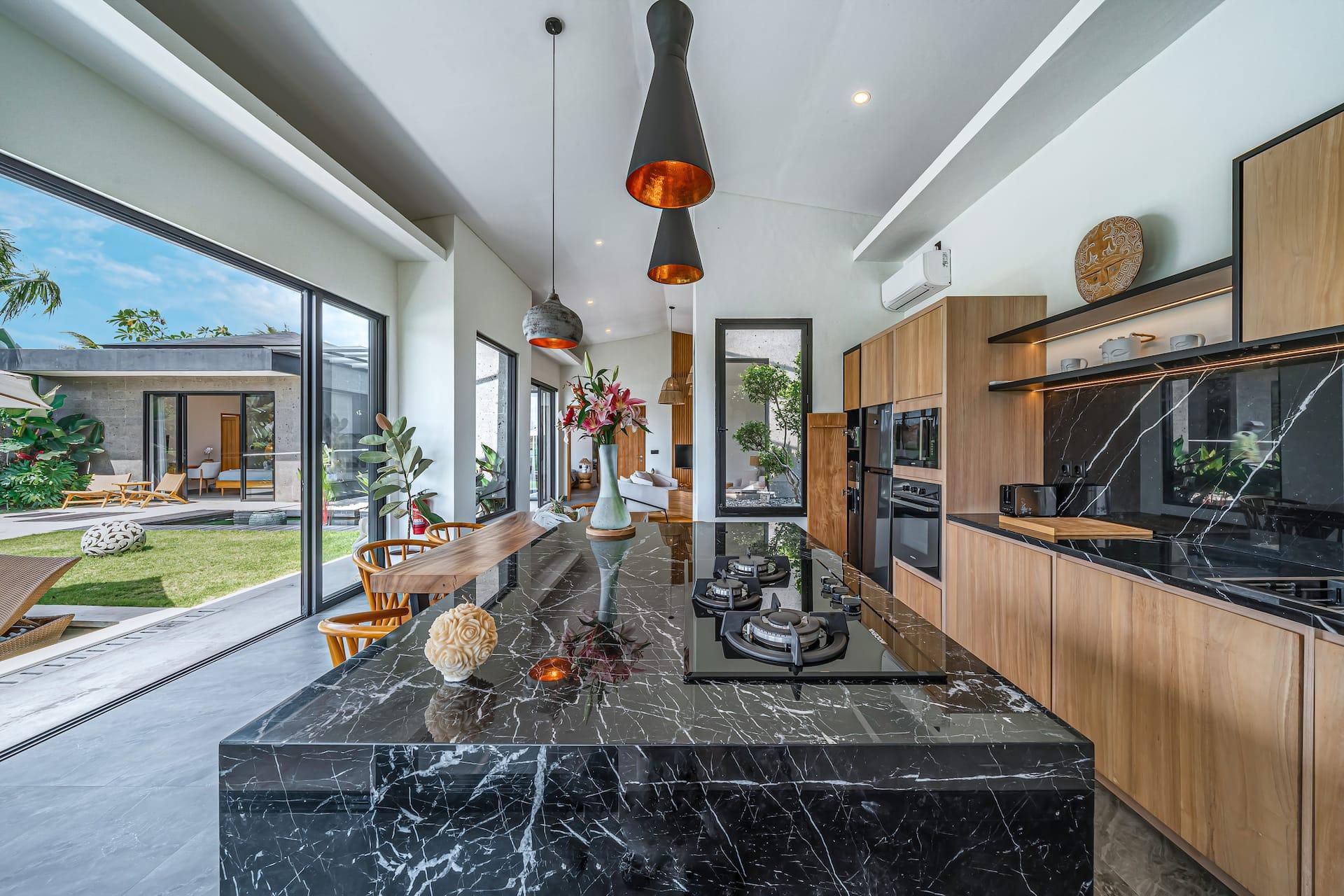 Live-edge dining table and black marble island with the rice fields framed in glass beyond