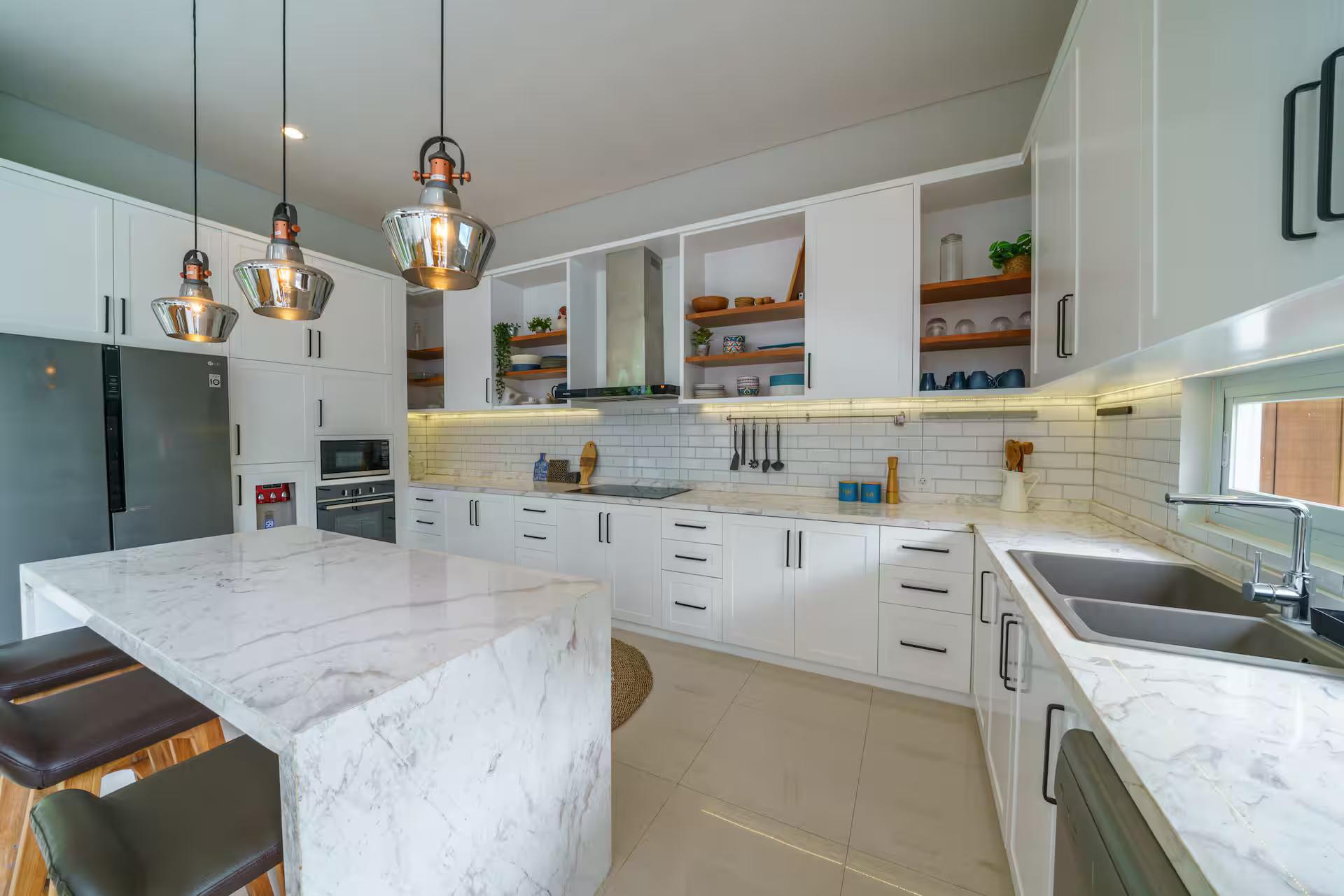 Marble kitchen island with a waterfall end and three copper-glass pendants above it