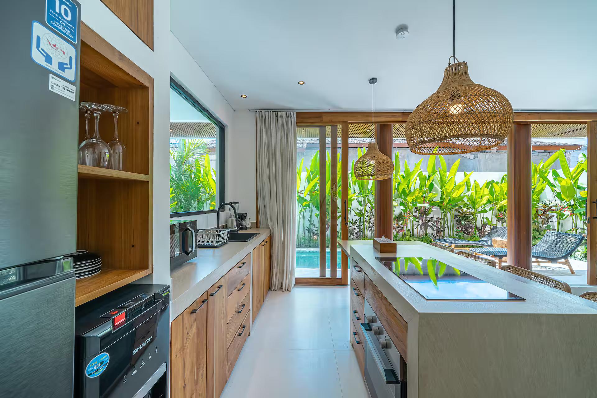 Kitchen at Villa Rindu Kamu with an island hob, timber cabinets and rattan pendants