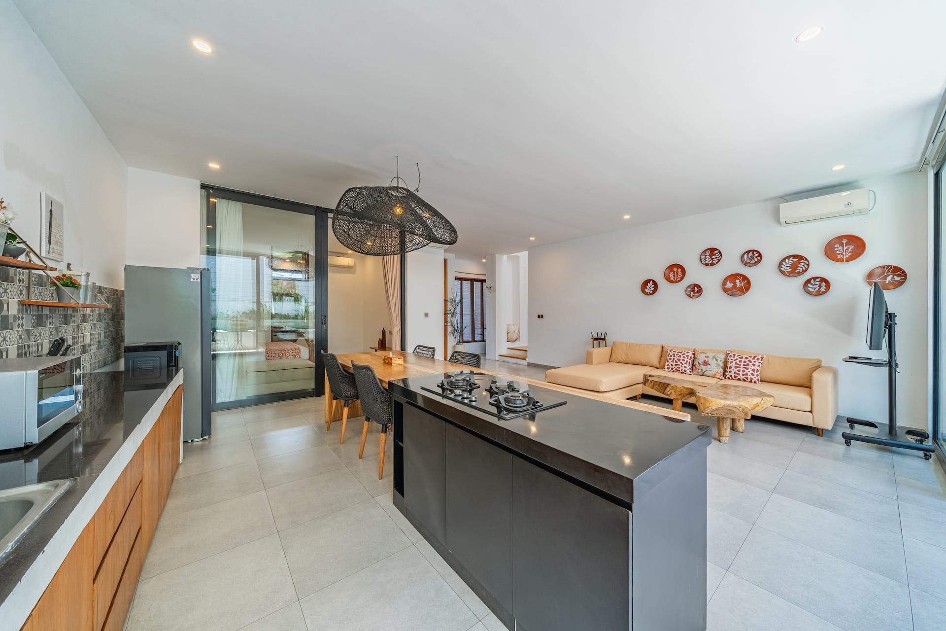 Black stone island and live-edge breakfast bar at Villa Athalla, the living room beyond