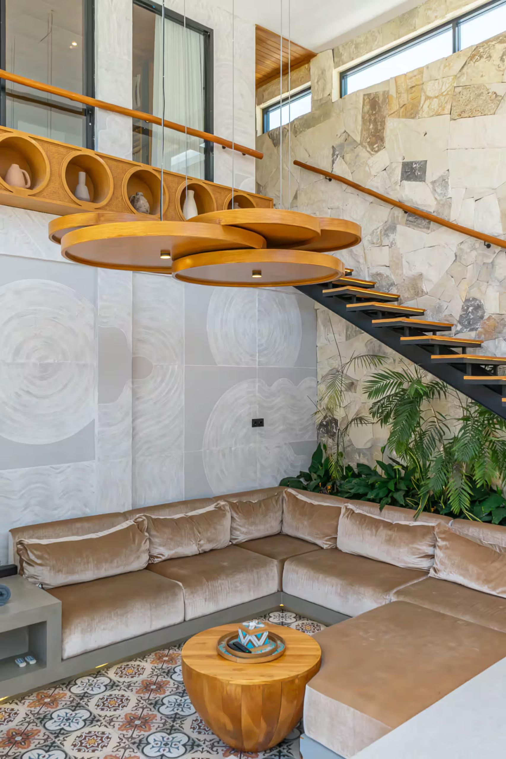 Suspended timber discs hanging above the sunken lounge and floating stair at Villa Asri Nyanyi