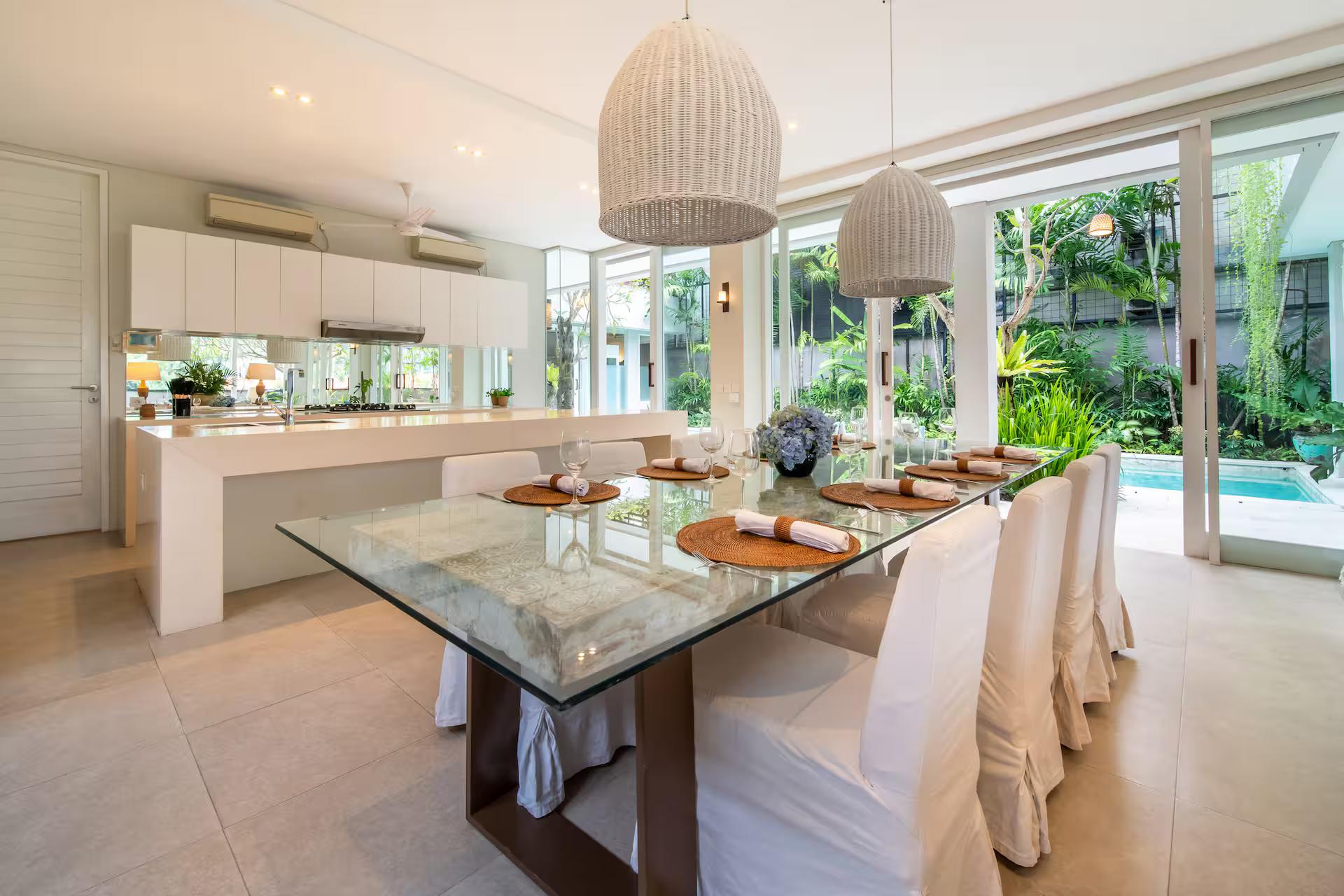 White island kitchen open to the dining table, with glass on two sides towards the pool