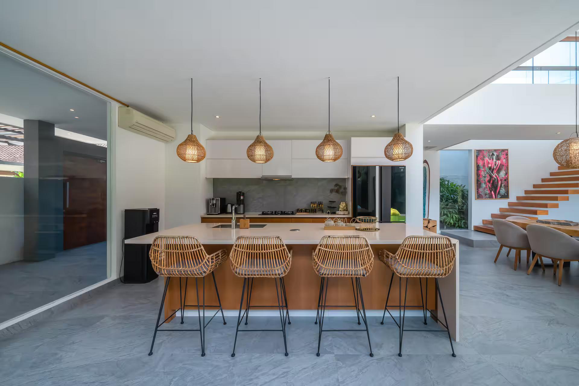 Kitchen island with rattan bar stools and copper pendants at The Jendela House